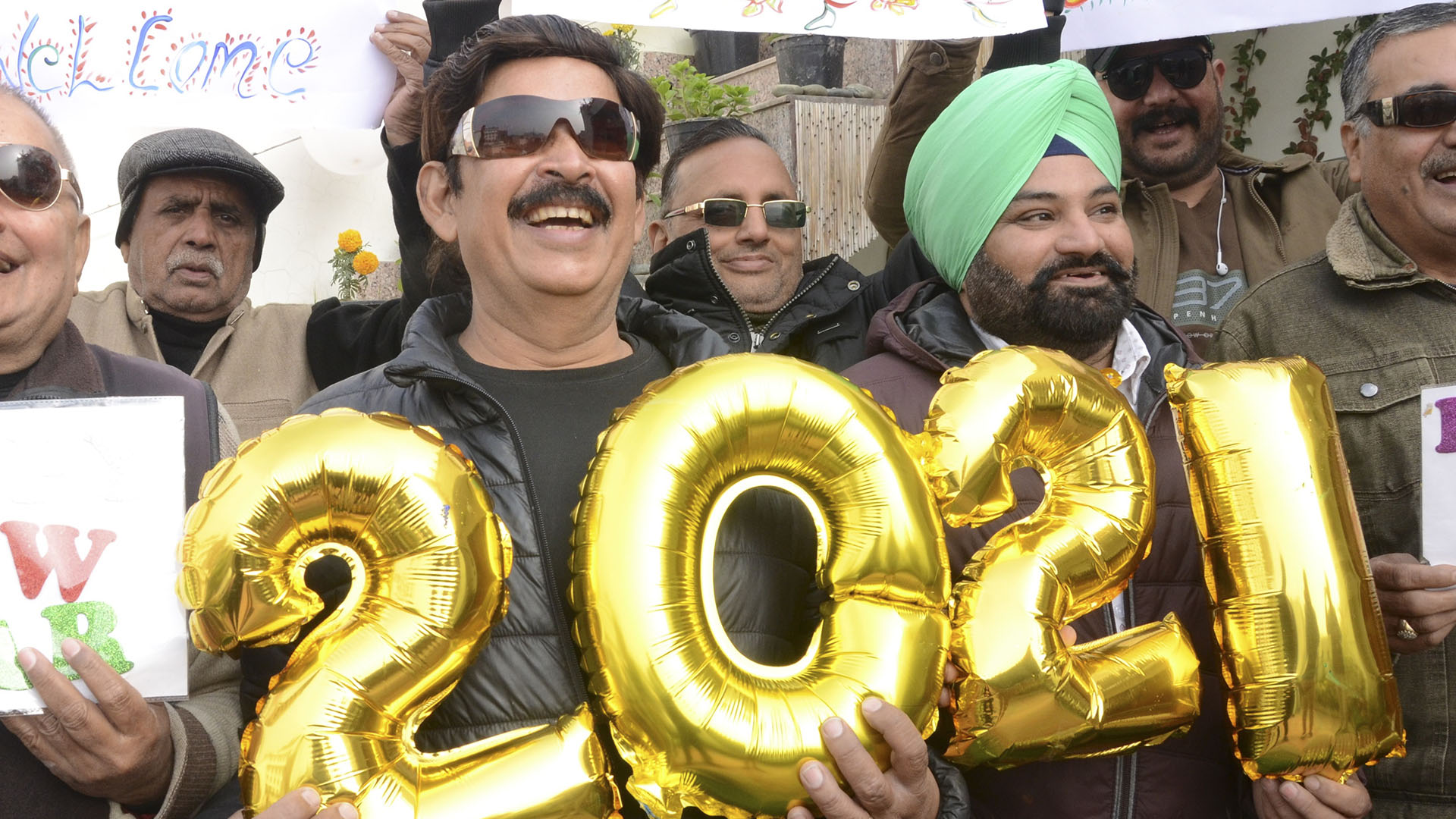 La gente sostiene pancartas y globos que forman el número 2021 durante las celebraciones del Año Nuevo en Amritsar, India (NARINDER NANU/ AFP)