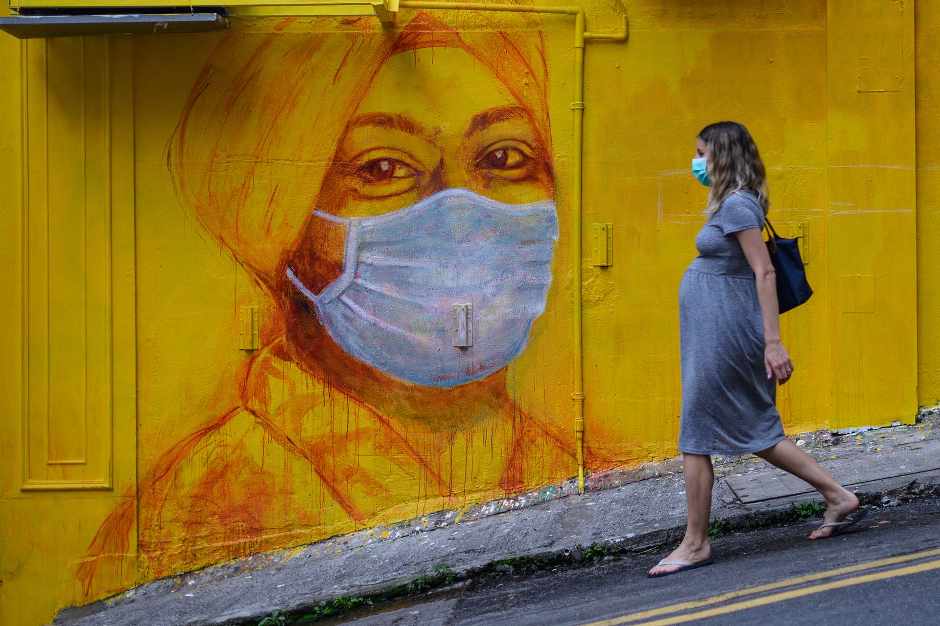 Una mujer embarazada pasa frente a un mural callejero en Hong Kong.