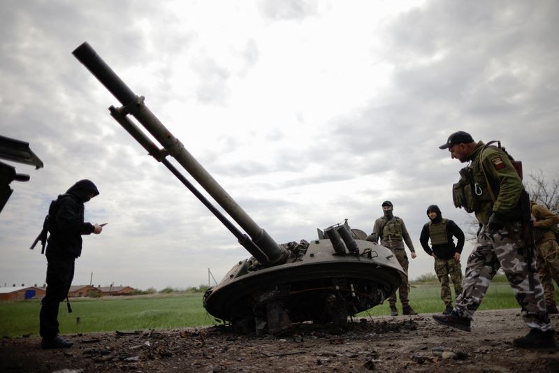 Ukrainian soldiers check some of a Russian weapon that was destroyed during the fighting