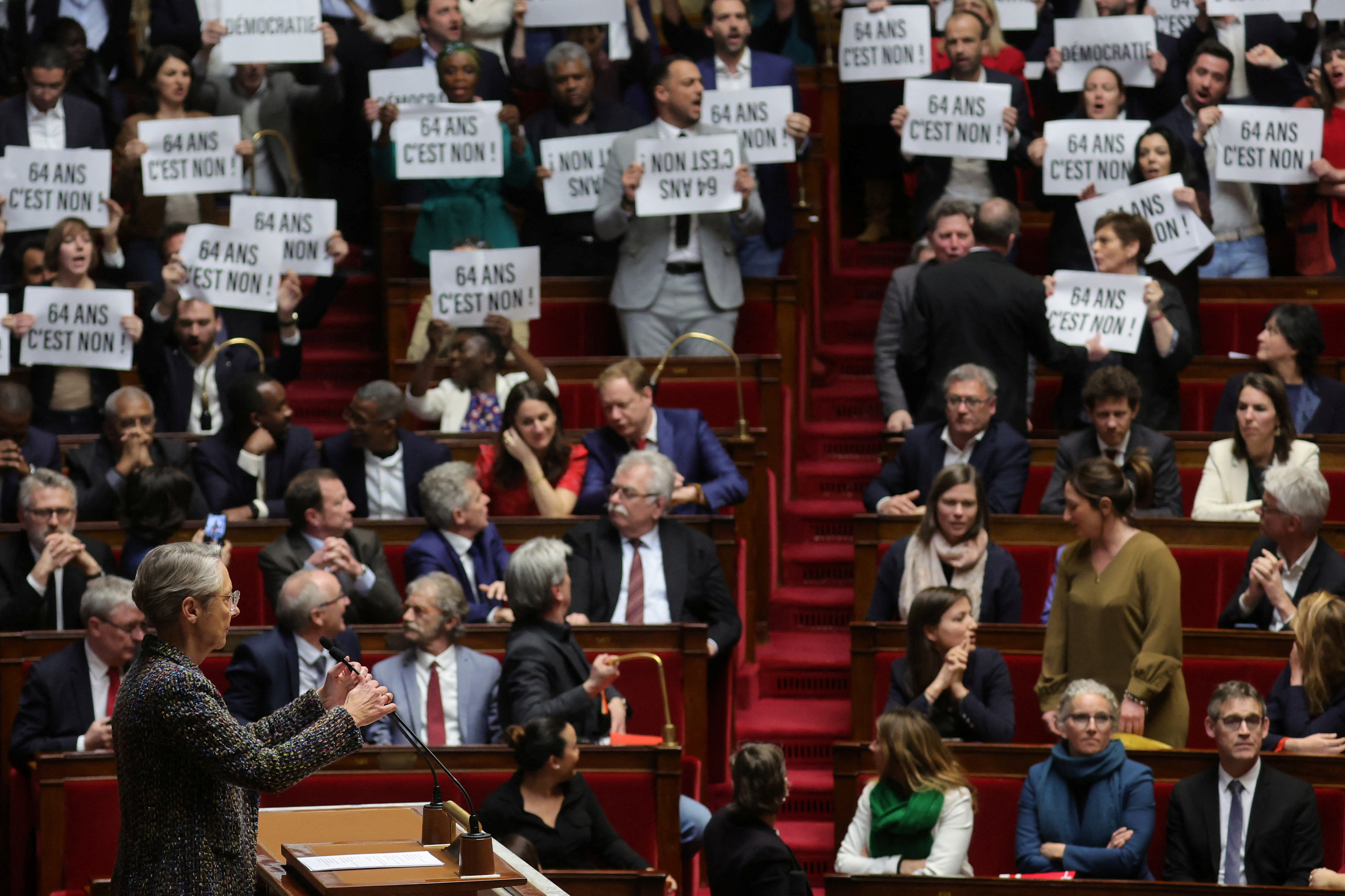 Miembros del parlamento francés muestran placas de rechazo a la reforma de pensiones, mientras la jefa del gabinete de Macron, Elisabeth Borne, aguarda para empezar a defender la aplicación del decreto (REUTERS/Pascal Rossignol)