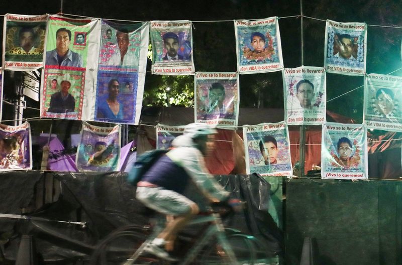 Foto de archivo: una persona pasa junto a una pared con fotos de algunos de los 43 estudiantes que desaparecieron de la escuela rural de maestros de Ayotzinapa (REUTERS/Henry Romero)