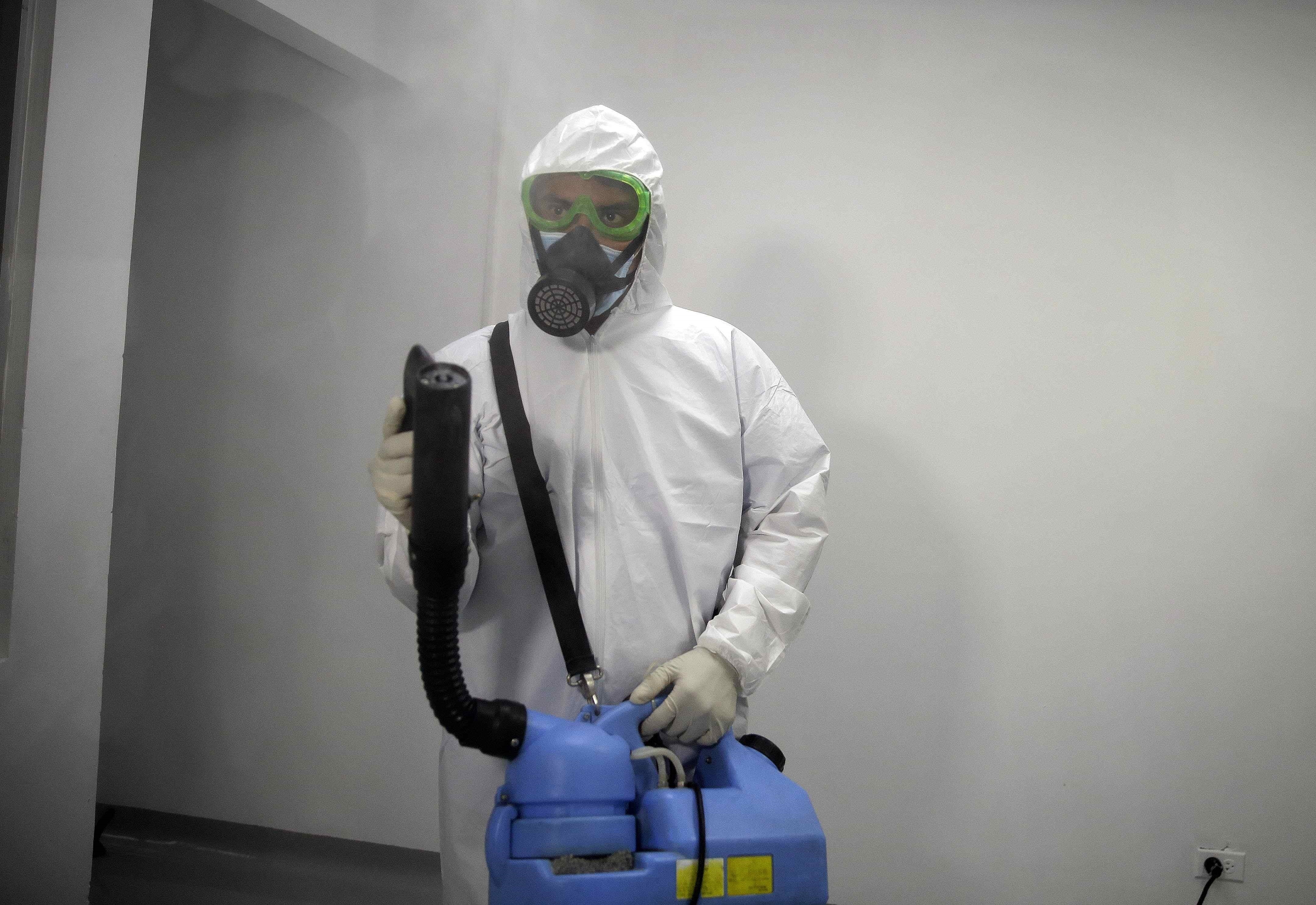 Un auxiliar del personal de aseo desinfecta un sector destinado para atender pacientes de COVID-19 en San Salvador (EFE/ Miguel Lemus)