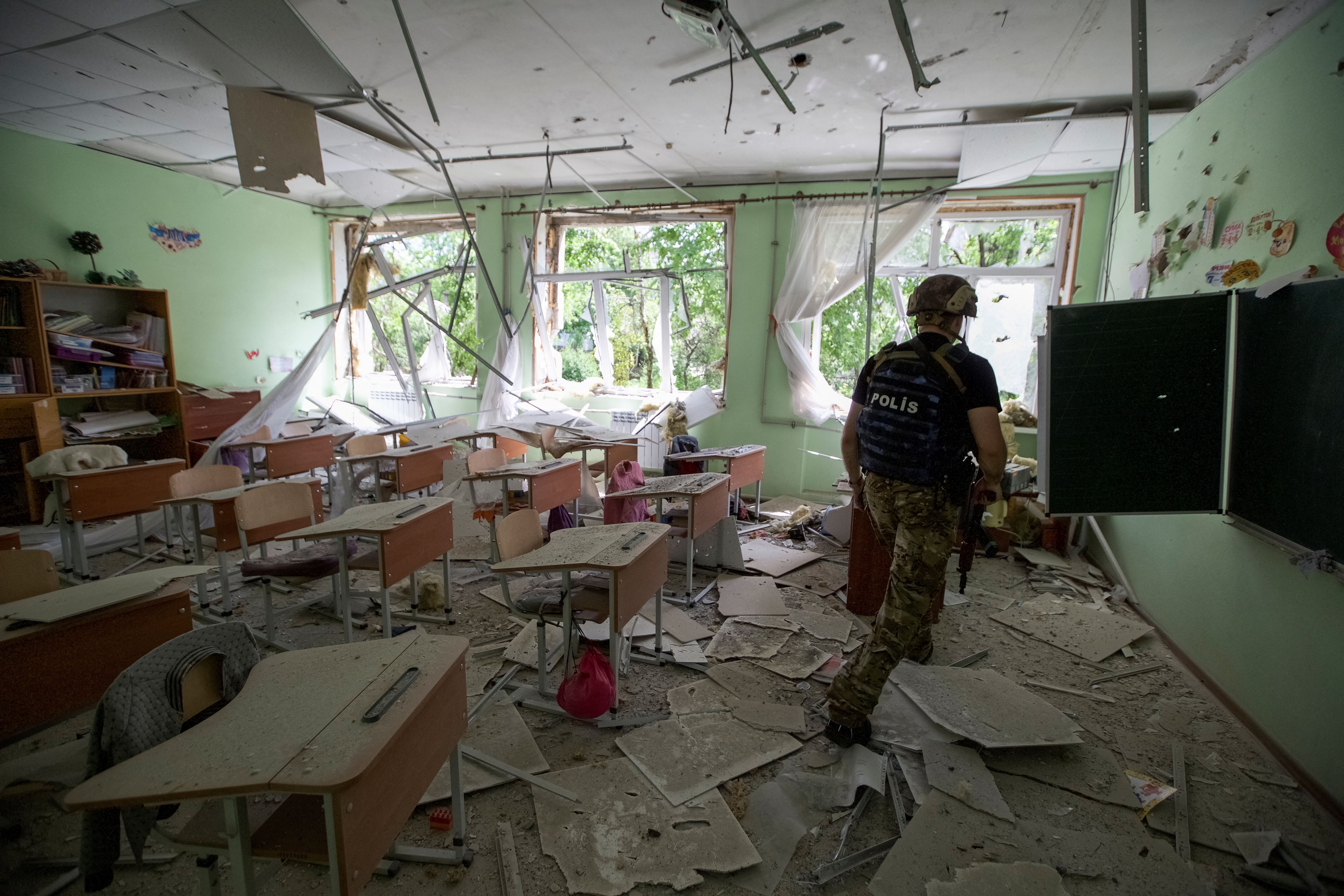 Un agente de policía revisa una escuela destruida tras un ataque de Rusia en la ciudad de Marinka, en la región de Donetsk, Ucrania (REUTERS/Anna Kudriavtseva)