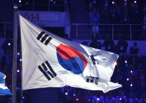 A picture taken on February 23, 2014 shows the flag of South Korea (R) flying during the Closing Ceremony of the Sochi Winter Olympics at the Fisht Olympic Stadium. The 2018 Winter Olympic games are scheduled to take place in Pyeongchang, South Korea.   AFP PHOTO / DAMIEN MEYER        (Photo credit should read DAMIEN MEYER/AFP/Getty Images)