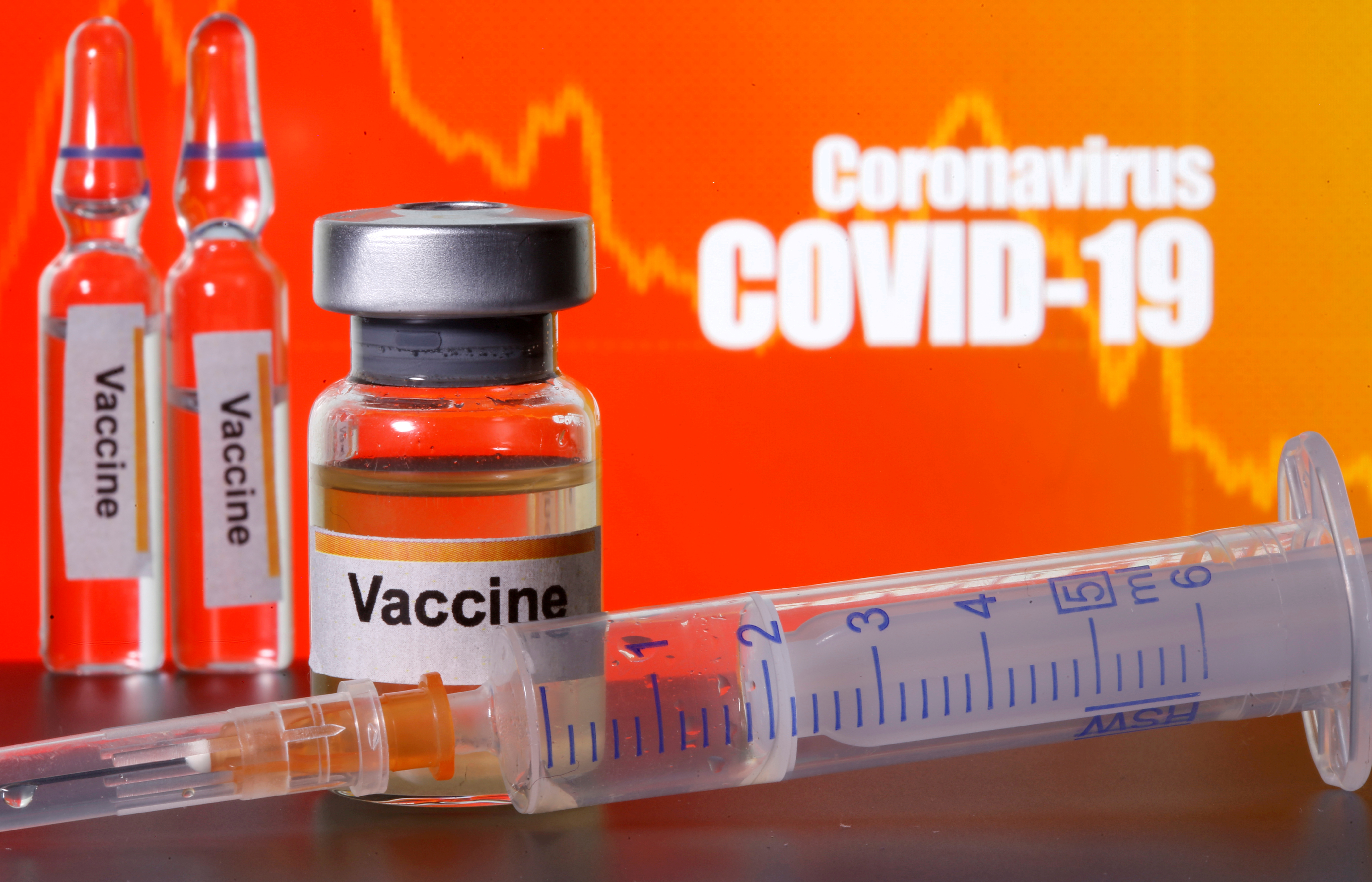 FILE PHOTO: Small bottles labeled with "Vaccine" stickers stand near a medical syringe in front of displayed "Coronavirus COVID-19" words in this illustration taken April 10, 2020. REUTERS/Dado Ruvic/Illustration/File Photo