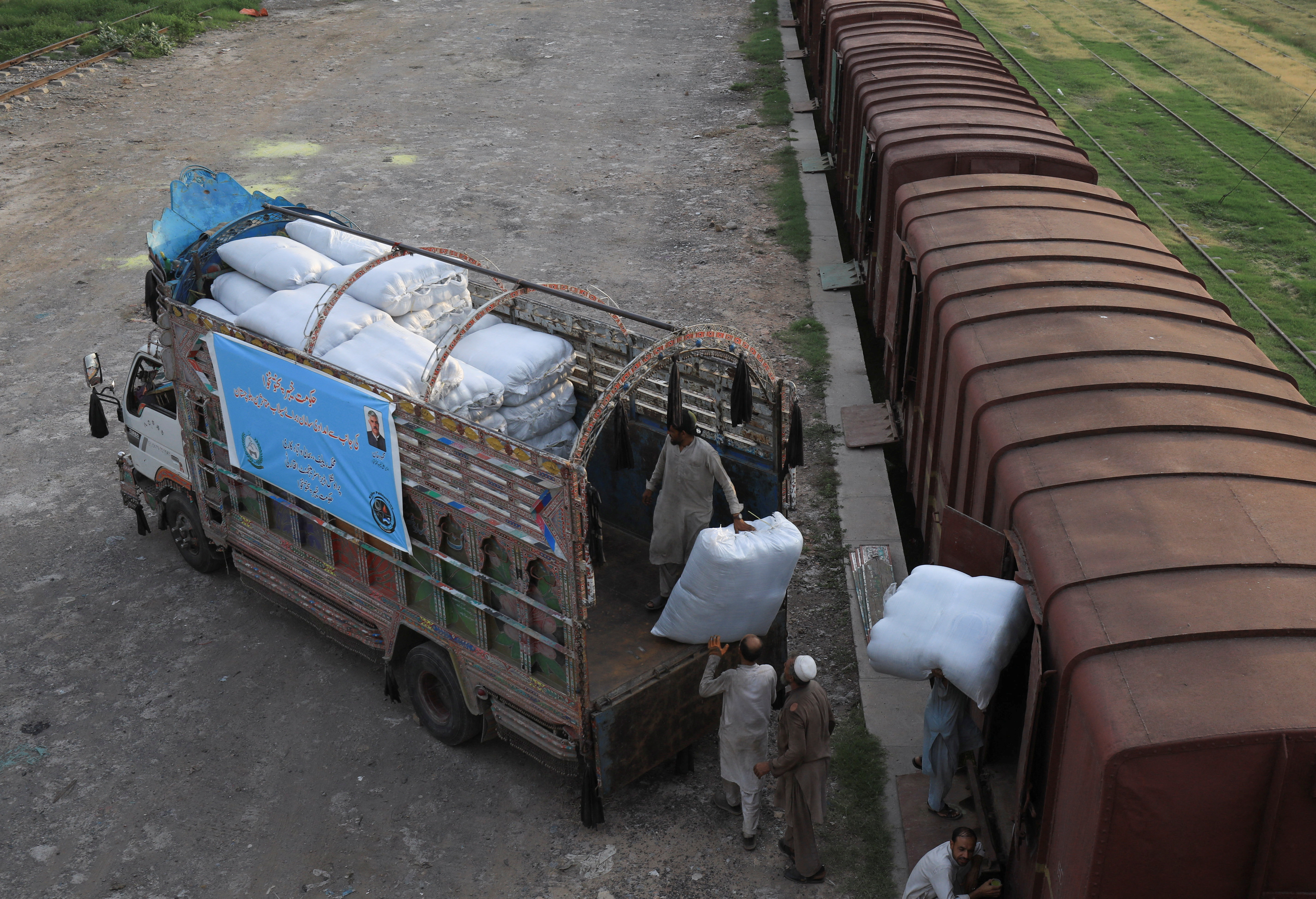 Trabajadores cargan sacos de productos de ayuda para las víctimas de las inundaciones en Baluchistán, en Peshawar (REUTERS/Fayaz Aziz)