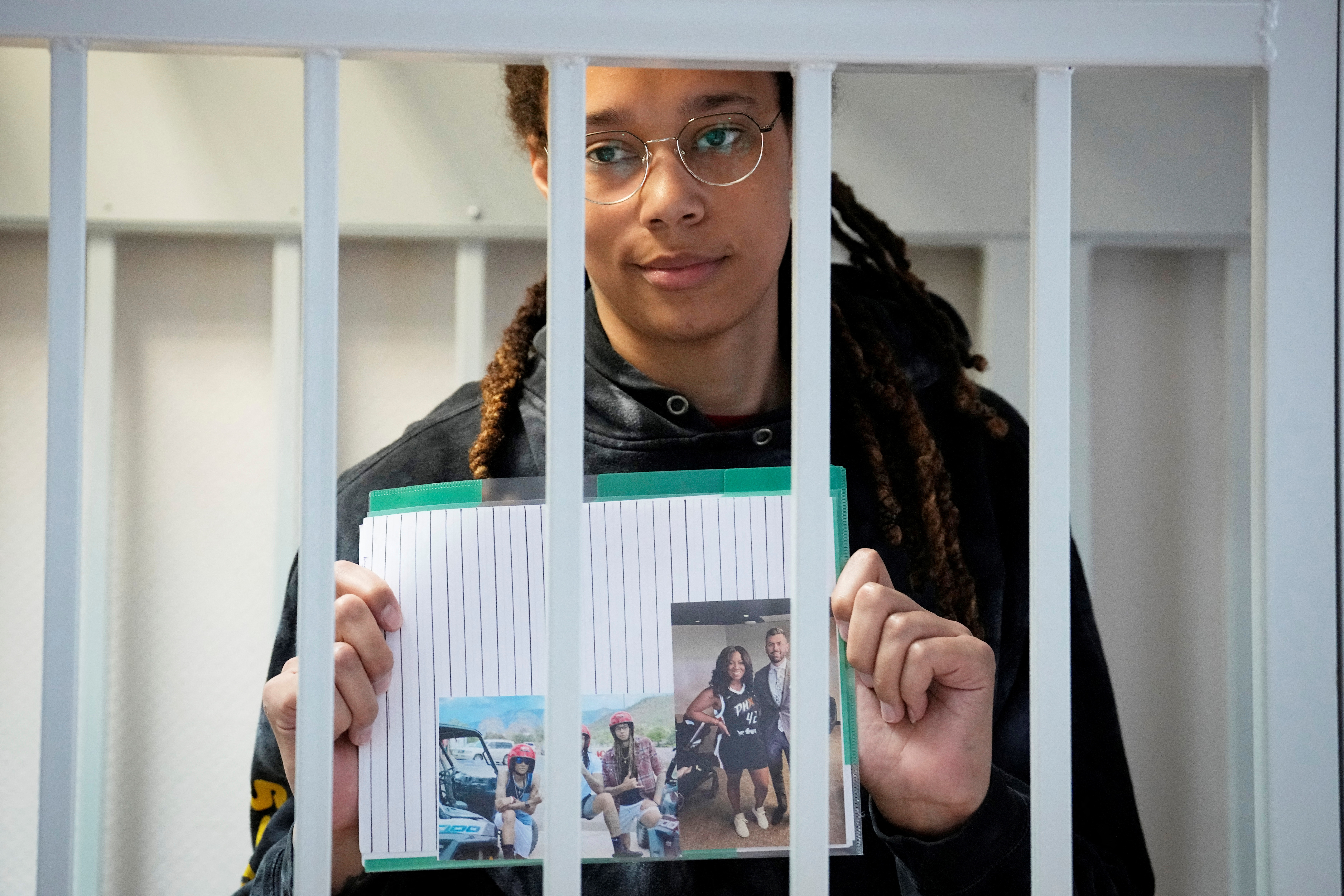 Brittney Griner sostiene imágenes de pie en una jaula en una sala de la corte antes de una audiencia, en Khimki a las afueras de Moscú, Rusia, 26 de julio de 2022. Alexander Zemlianichenko/Pool vía REUTERS