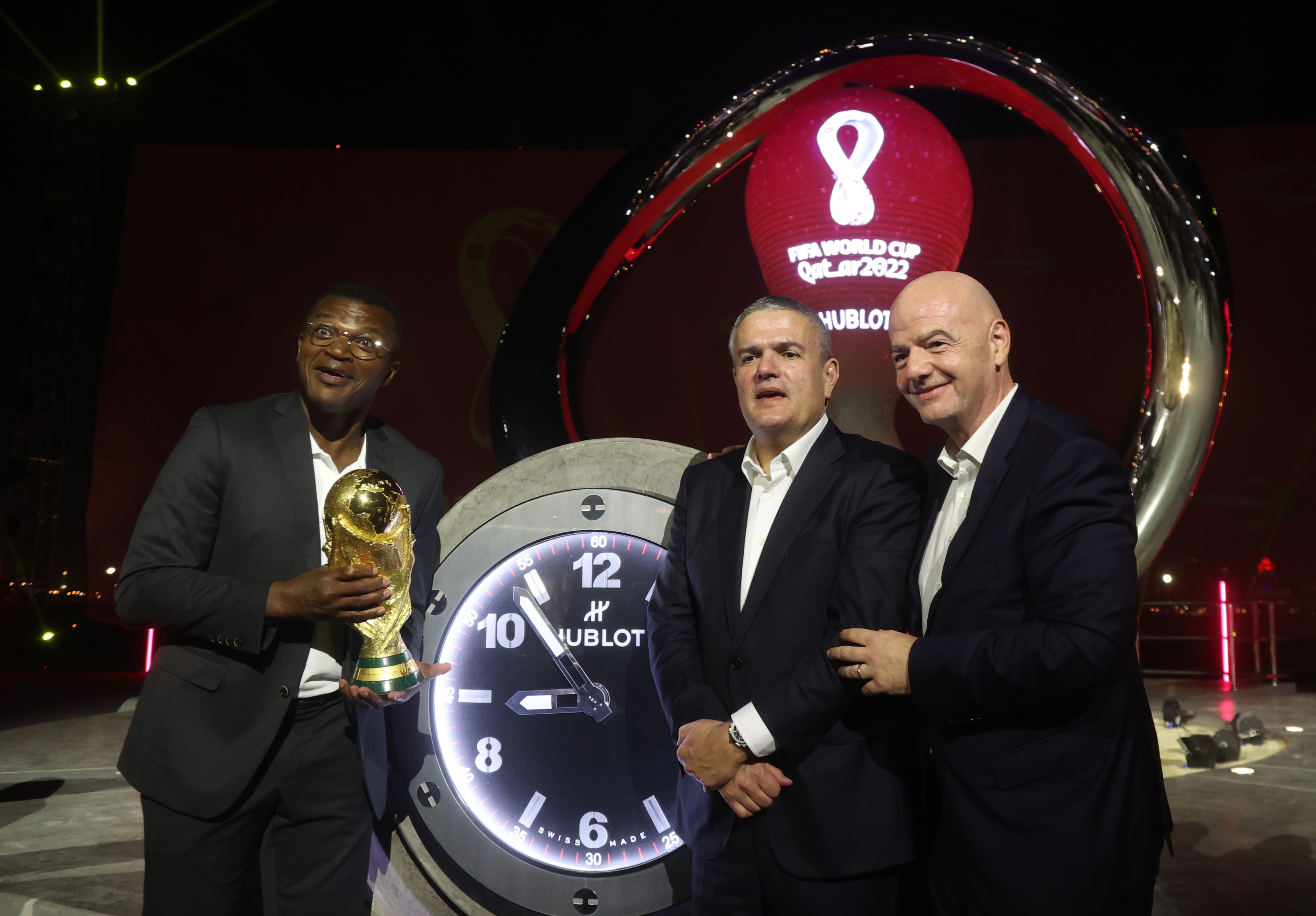 Soccer Football - One year to go until the 2022 World Cup in Qatar - Corniche Fishing Spot, Doha, Qatar - November 21, 2021 Former France player Marcel Desailly, CEO of Hublot Ricardo Guadalupe and FIFA president Gianni Infantino pose with the world cup REUTERS/Ibraheem Al Omari