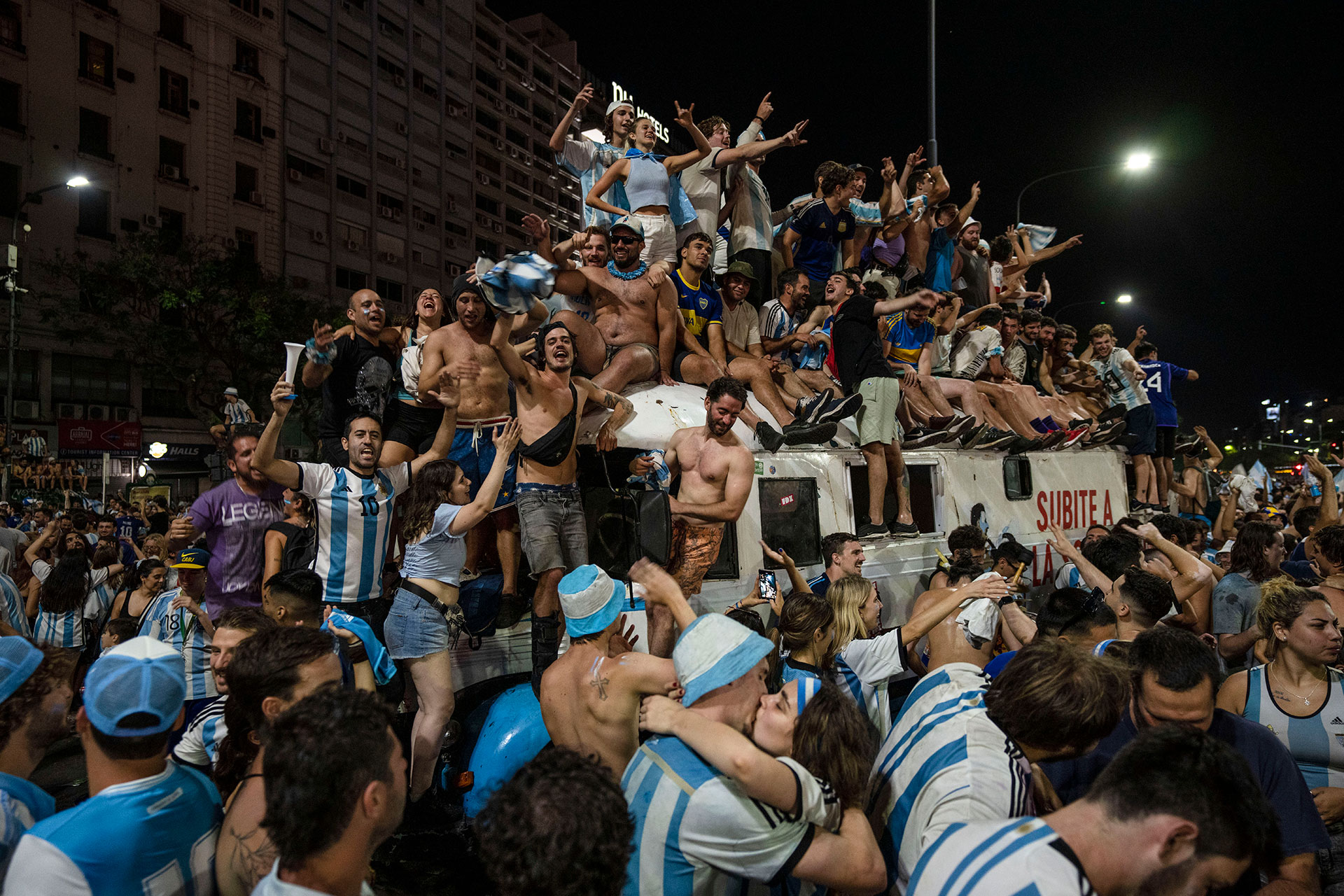 A couple kiss as other soccer fans celebrate Argentina's victory over France in the World Cup final soccer match, in Buenos Aires, Argentina, Sunday, Dec. 18, 2022. (AP Photo/Rodrigo Abd)