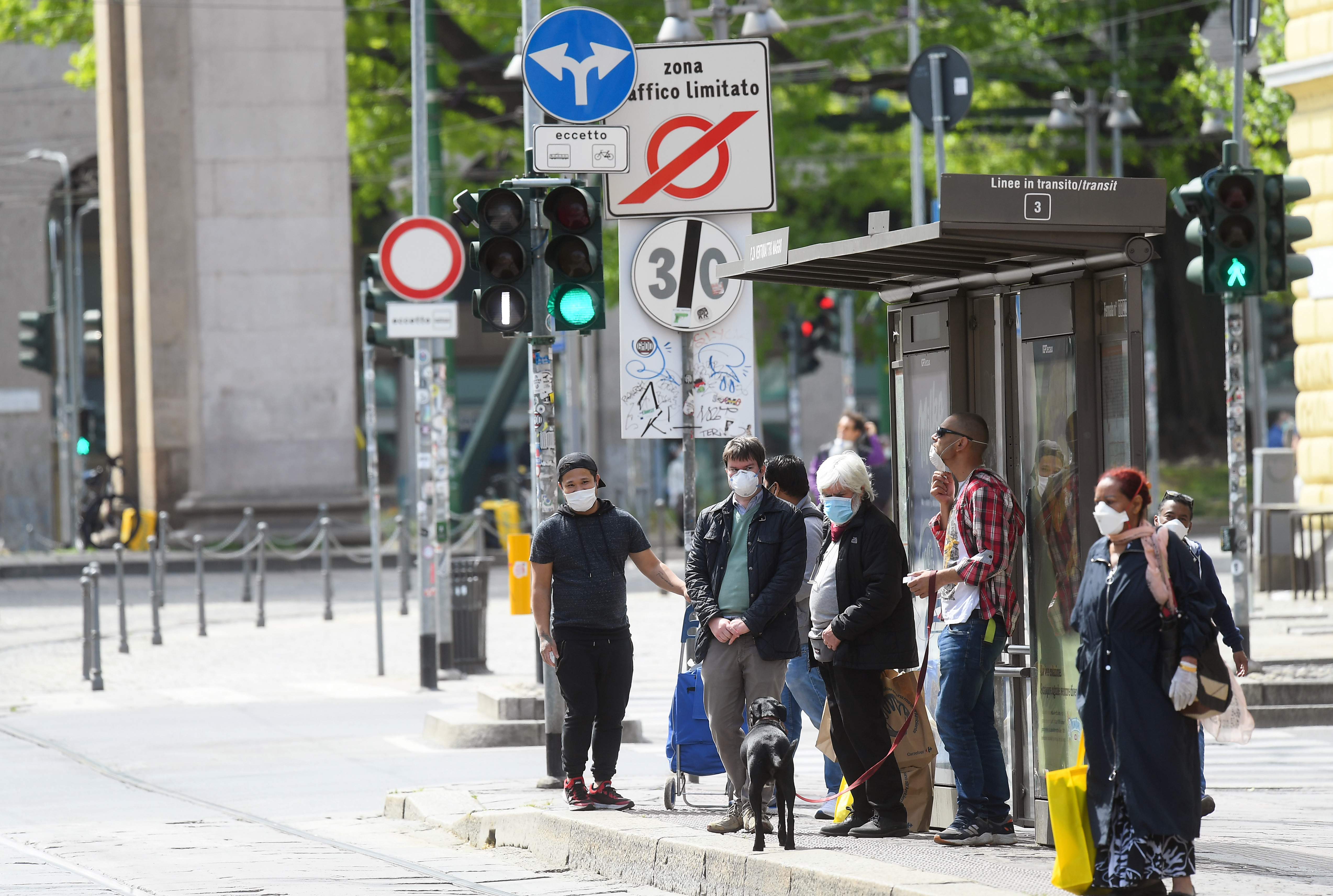 Personas con máscaras protectoras esperan en una parada de autobús en una calle cada vez más concurrida, en medio del brote del 
coronavirus, en Milán, Italia (Reuters)