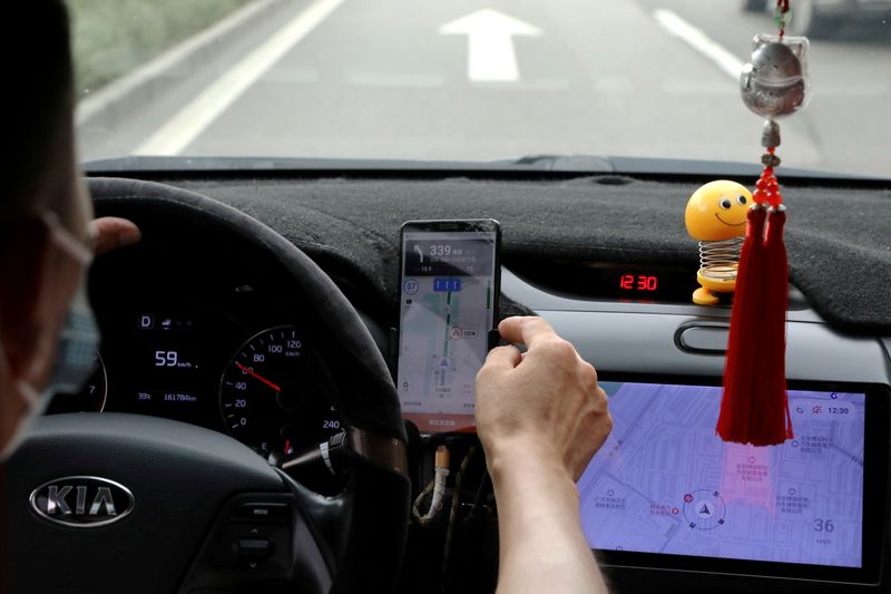 Un conductor del servicio chino de transporte compartido Didi conduce con un teléfono que muestra un mapa de navegación en la app de Didi, en Pekín (Foto: REUTERS)