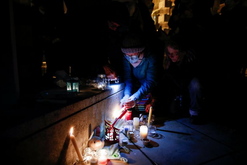Una persona enciende una vela mientras la gente rinde homenaje a los 27 migrantes que murieron cuando su bote se desinfló cuando intentaban cruzar el Canal de la Mancha, en el Parque Richelieu en Dunkerque, Francia, 25 noviembre 2021.
REUTERS/Johanna Geron