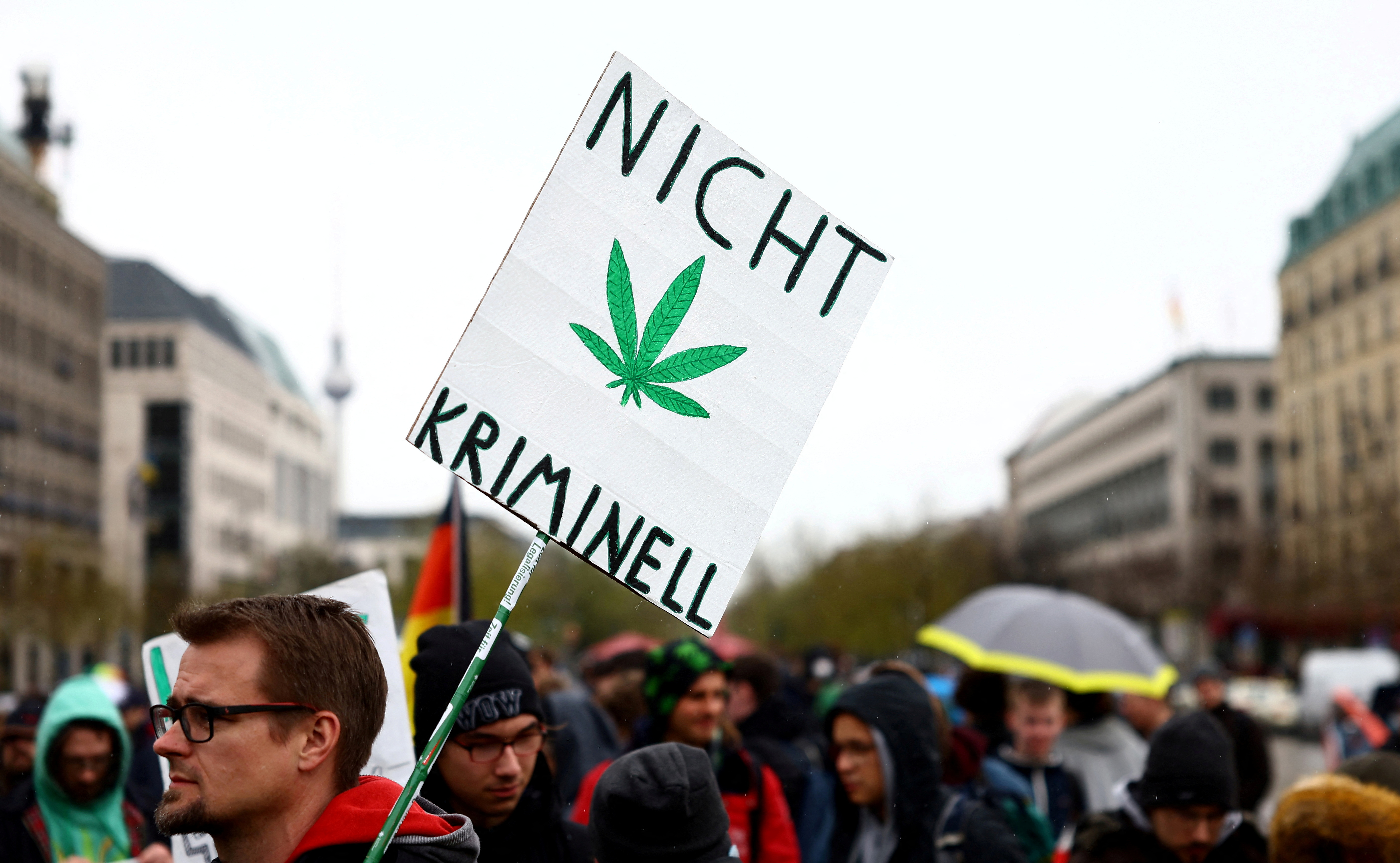 Un hombre lleva un cartel que dice "No criminal" mientras participa en una reunión con activistas de la marihuana para conmemorar el día mundial anual del cannabis y protestar por la legalización de la marihuana, frente a la Puerta de Brandenburgo, en Berlín, Alemania, el 20 de abril de 2022 (REUTERS/Lisi Niesner)