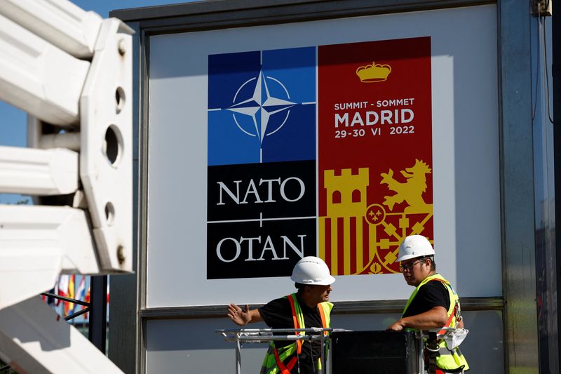 Varios trabajadores cuelgan los carteles que anuncian la celebración de la cumbre de la OTAN en Madrid, España.