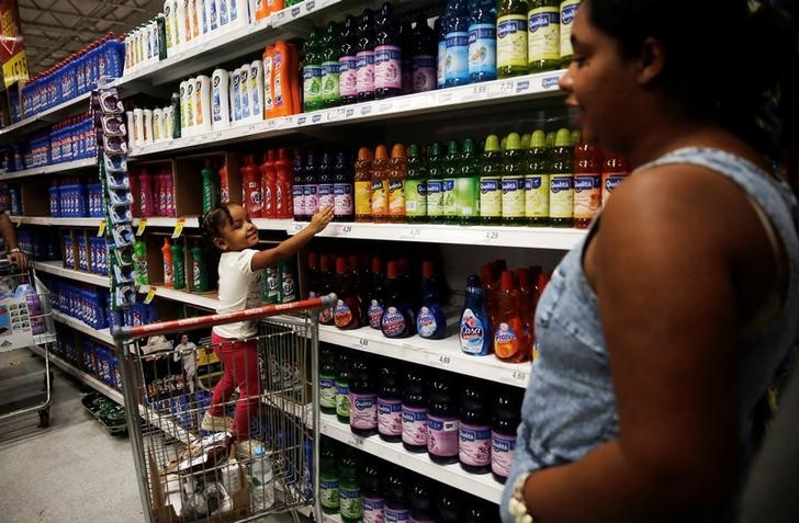 Un niño se para en un carrito de compras mientras señala los productos de limpieza junto a su madre en un supermercado en San Pablo (REUTERS/Nacho Doce/Archivo)