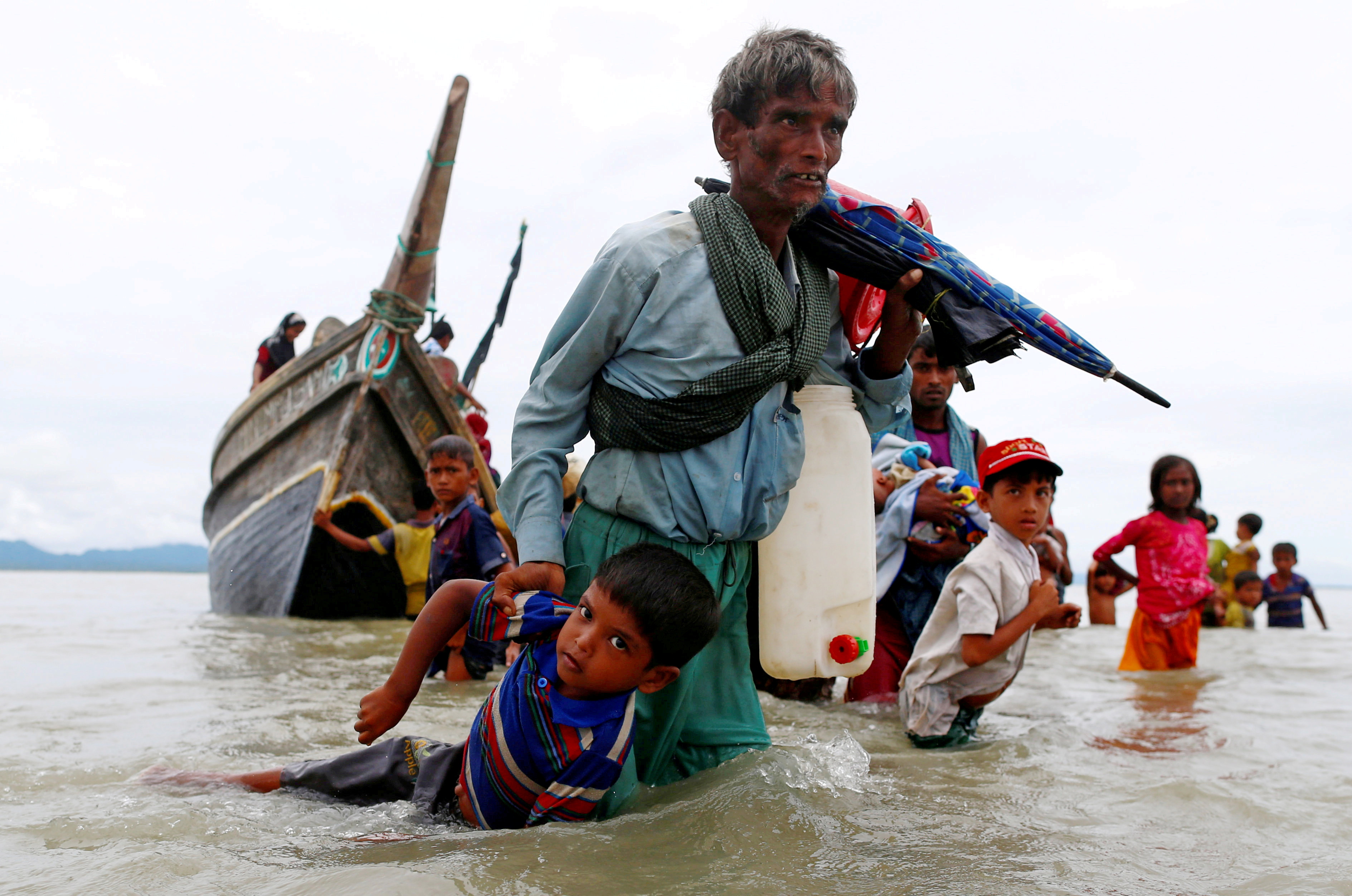 Un hombre refugiado rohingya tira de un niño mientras caminan hacia la orilla después de cruzar la frontera entre Bangladesh y Myanmar en barco a través de la Bahía de Bengala en Shah Porir Dwip, Bangladesh, 10 de septiembre de 2017.