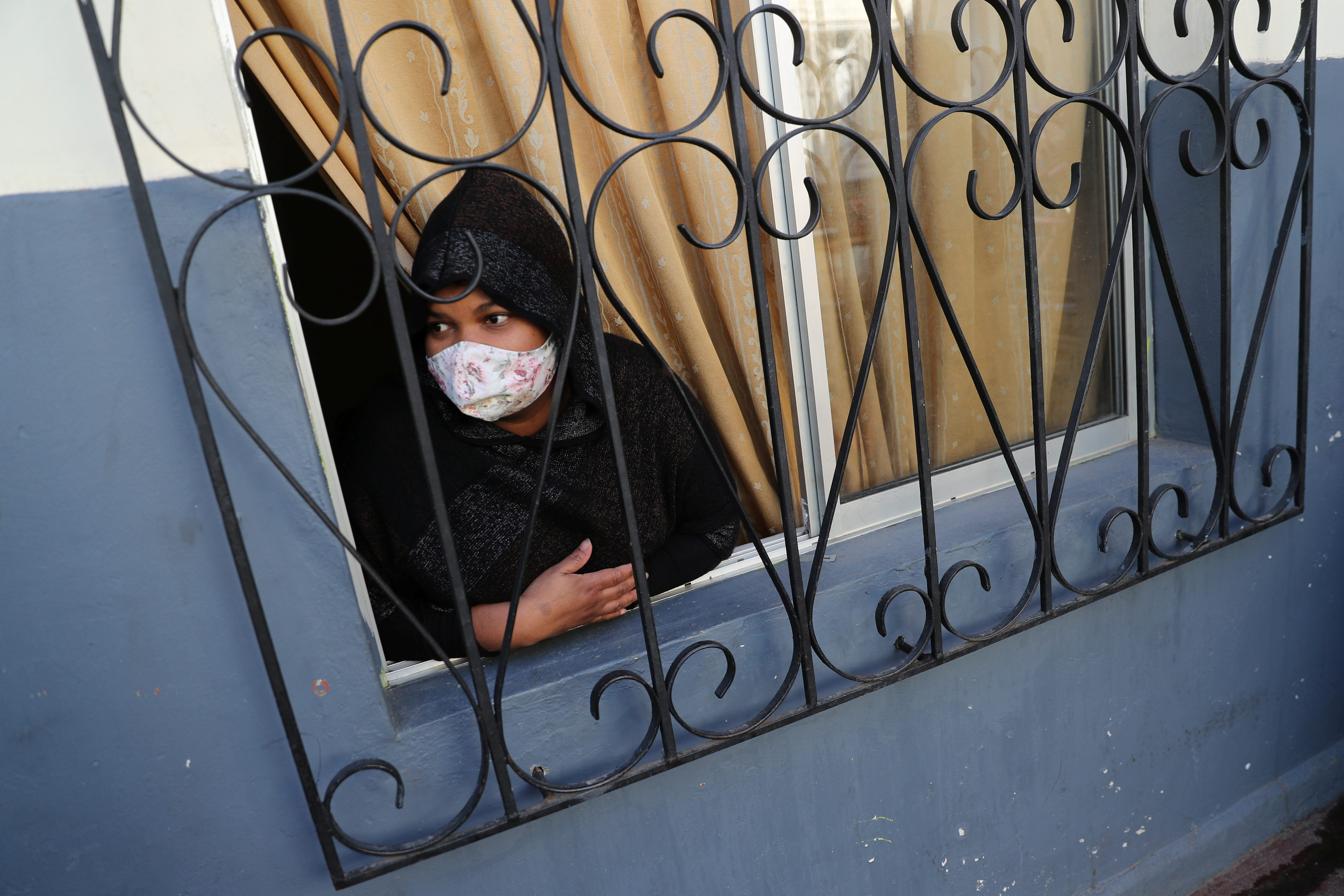 Una inmigrante peruana con barbijo mira por la ventana en Santiago, Chile (REUTERS/Ivan Alvarado)
