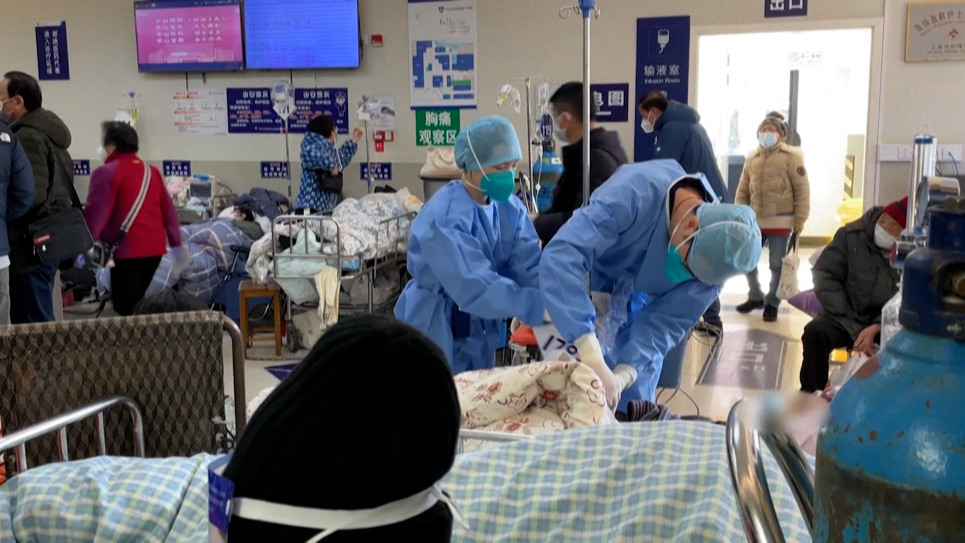 Los médico atienden a un paciente con COVID en medio del caos de un recinto repleto de contagiados por el virus en China 