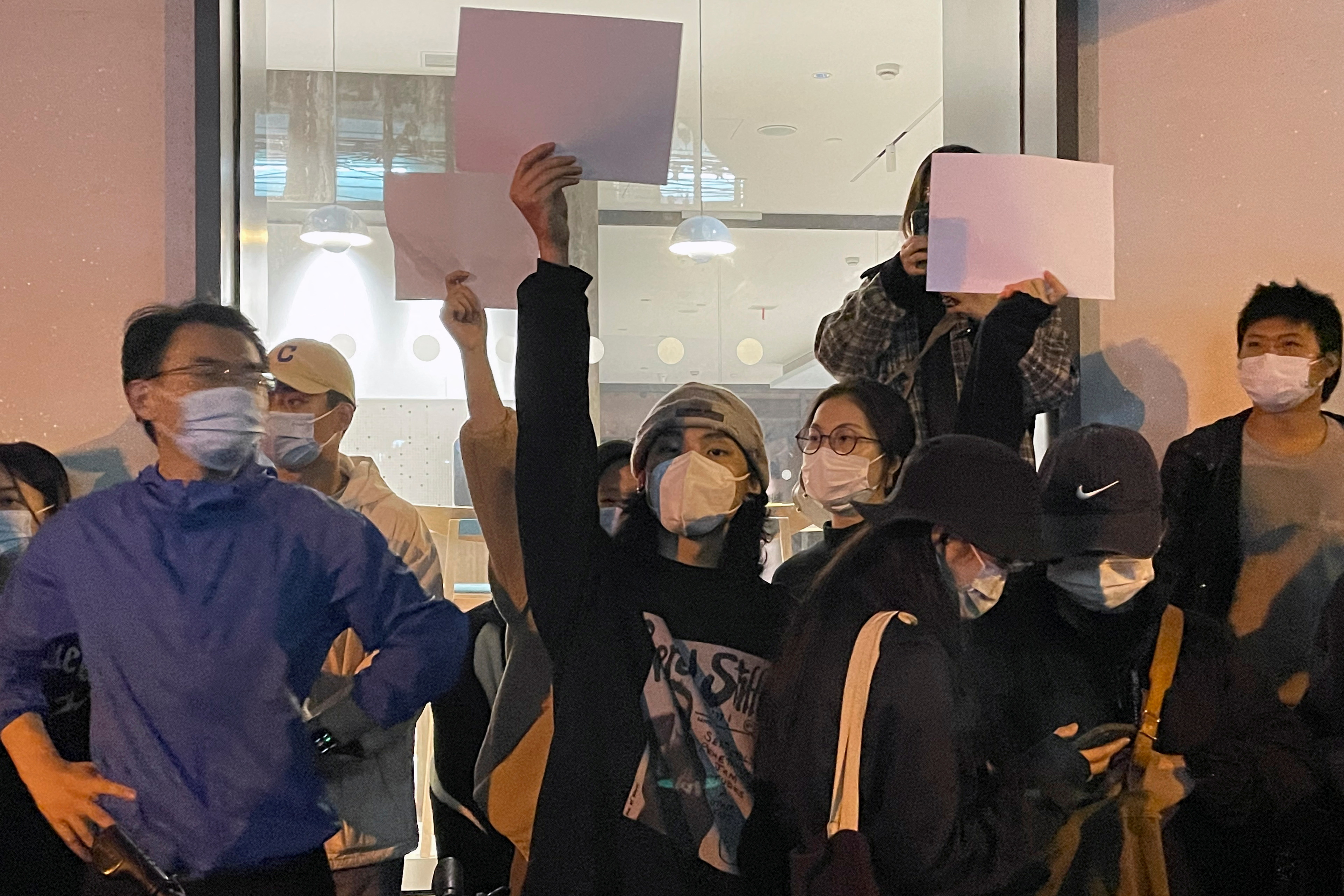 La gente sostiene hojas de papel en blanco durante una manifestación contra las restricciones de COVID-19 tras el mortal incendio de Urumqi, en Shanghái, China, el 27 de noviembre de 2022. (REUTERS/Josh Horwitz)