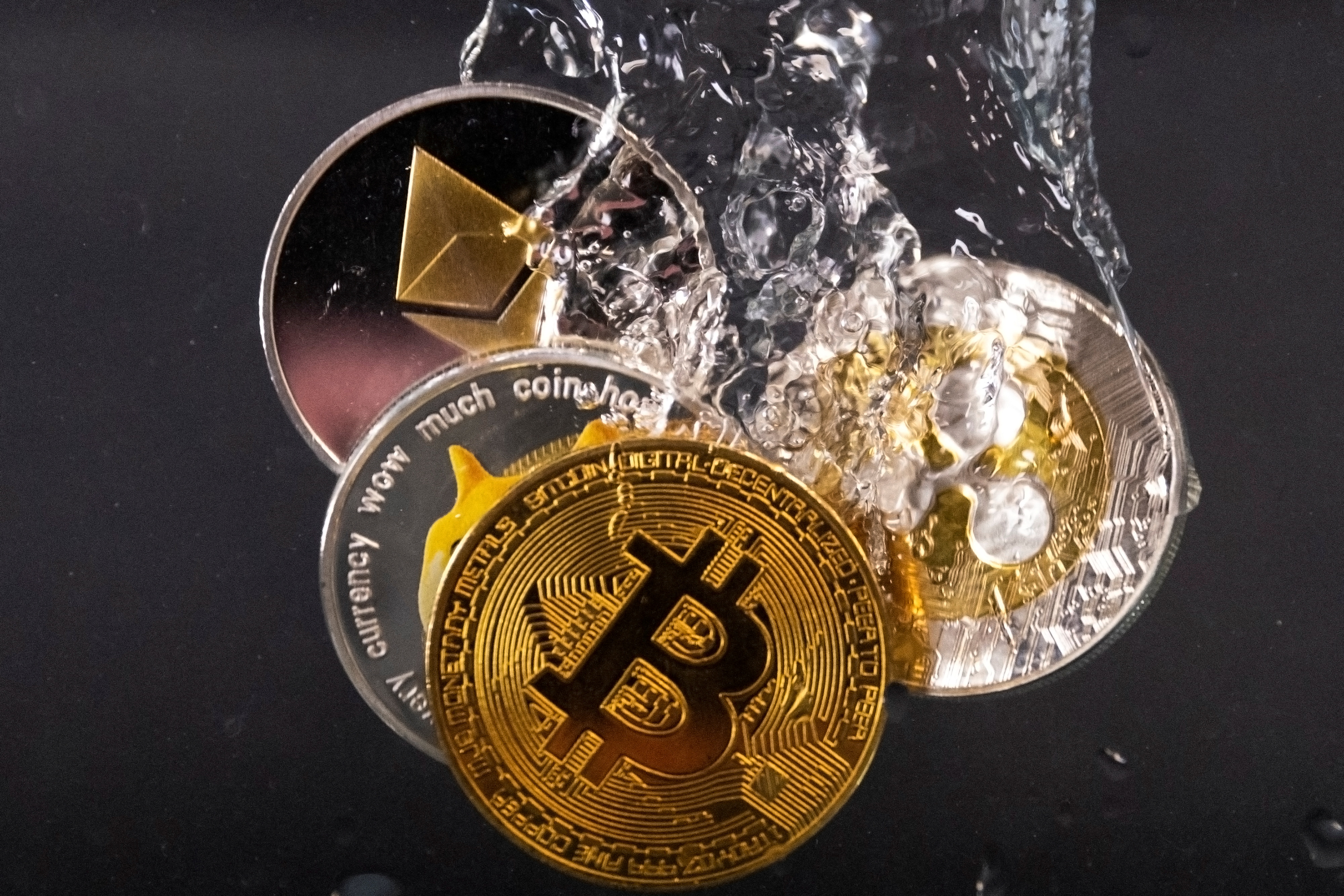 Souvenir tokens representing cryptocurrency networks Bitcoin, Ethereum, Dogecoin and Ripple plunge into water in this illustration taken May 17, 2022. REUTERS/Dado Ruvic/Illustration
