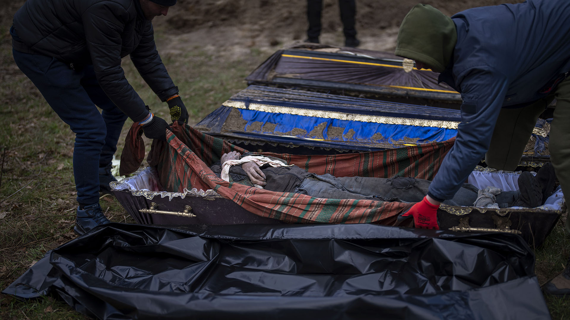 Voluntarios pusieron en una bolsa el cuerpo de un civil asesinado por el ejército ruso, después de haber sido sacado de una fosa común. (AP Foto/Emilio Morenatti) 