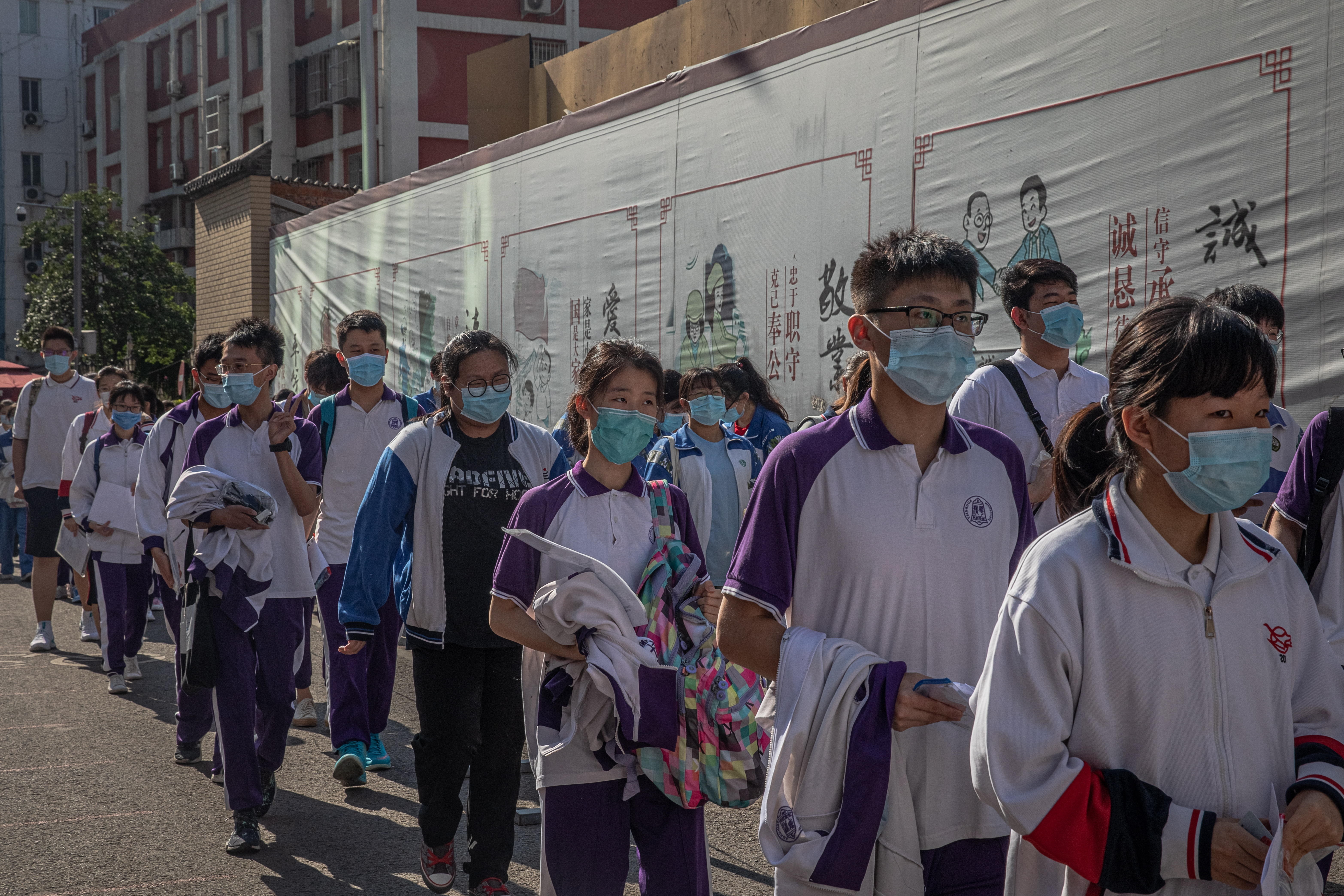 Los estudiantes con mascarillas esperan para entrar en una escuela para asistir al primer día de los exámenes anuales de ingreso a la universidad nacional de China en Pekín. EFE/EPA/ROMAN PILIPEY
