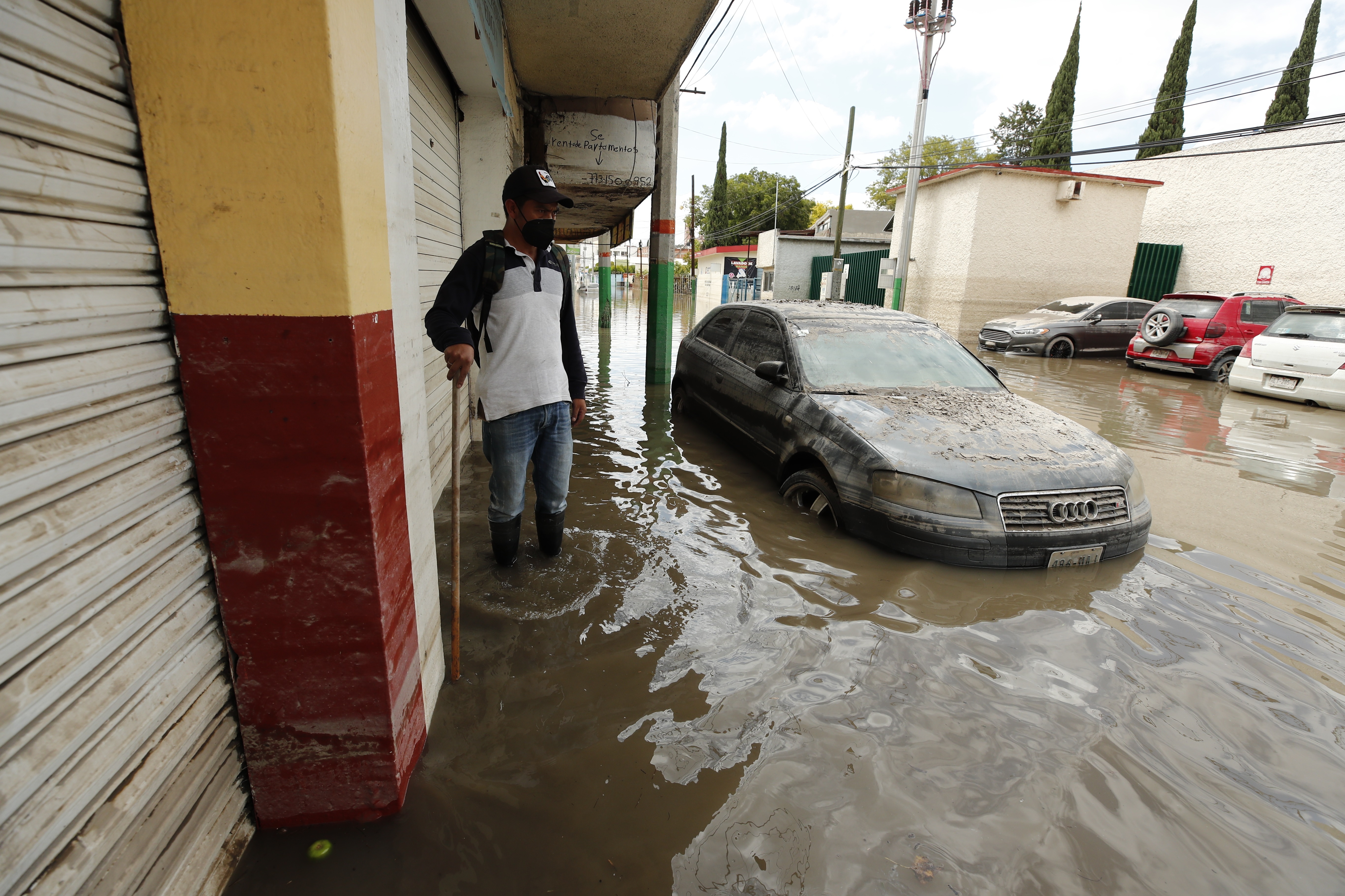 Un hombre camina junto a un vehículo que permanece atrapado en una inundación producida por fuertes lluvias, el 9 de septiembre de 2021, en la ciudad de Tula, en Hidalgo (México). EFE/ José Méndez
