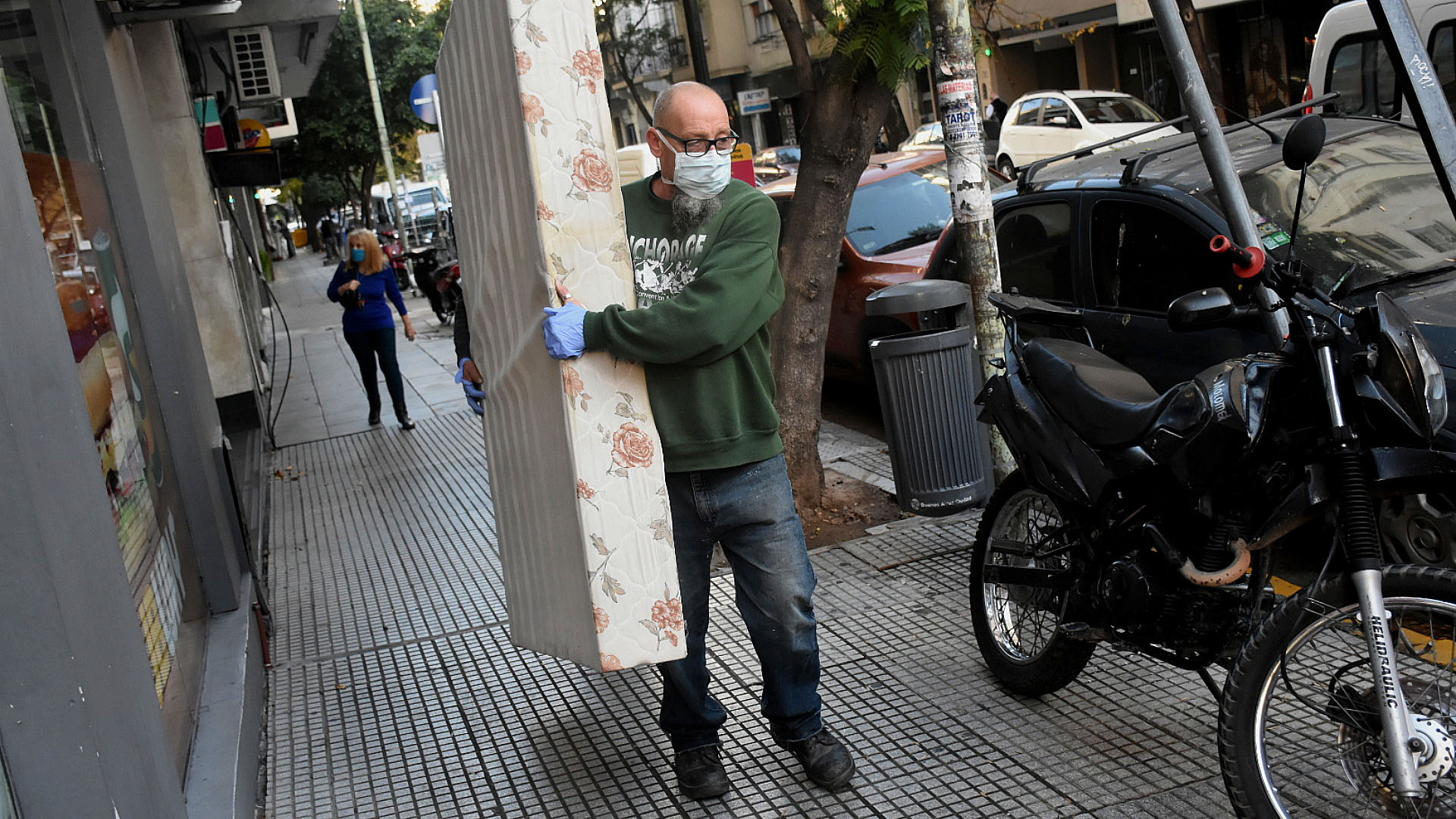 Un empleado de una empresa mudanzas traslada un colchón en medio de la calle