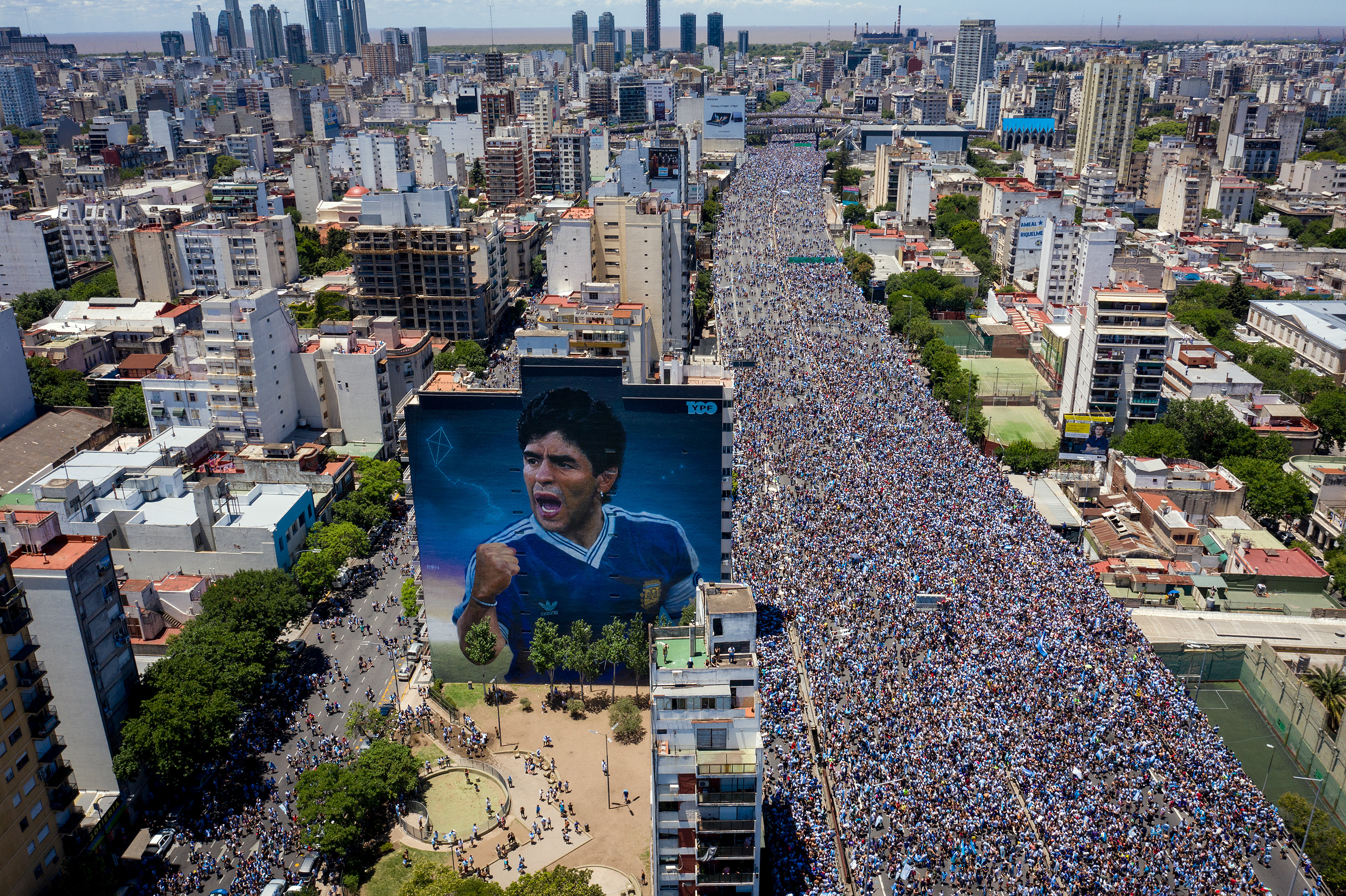 Carte postale de la foule dans la rue à côté de l'impressionnante peinture murale de Diego Maradona (Charly Díaz Azcue)
