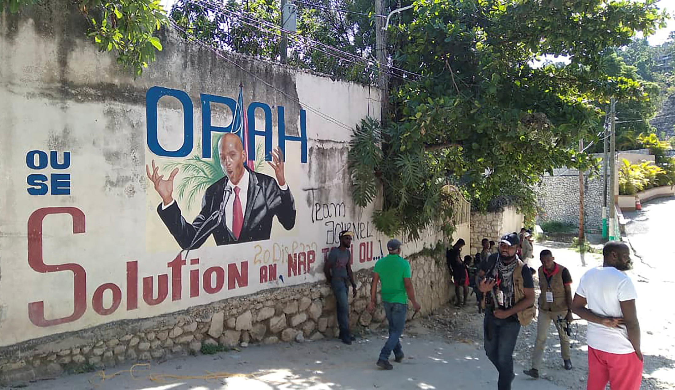La gente camina delante de un pared con un mural que representa a Jovenel Moise luego de que fuera asesinado por atacantes no identificados en su residencia privada, en Puerto Príncipe, Haití 7 de julio de 2021 (REUTERS/Robenson Sanon)