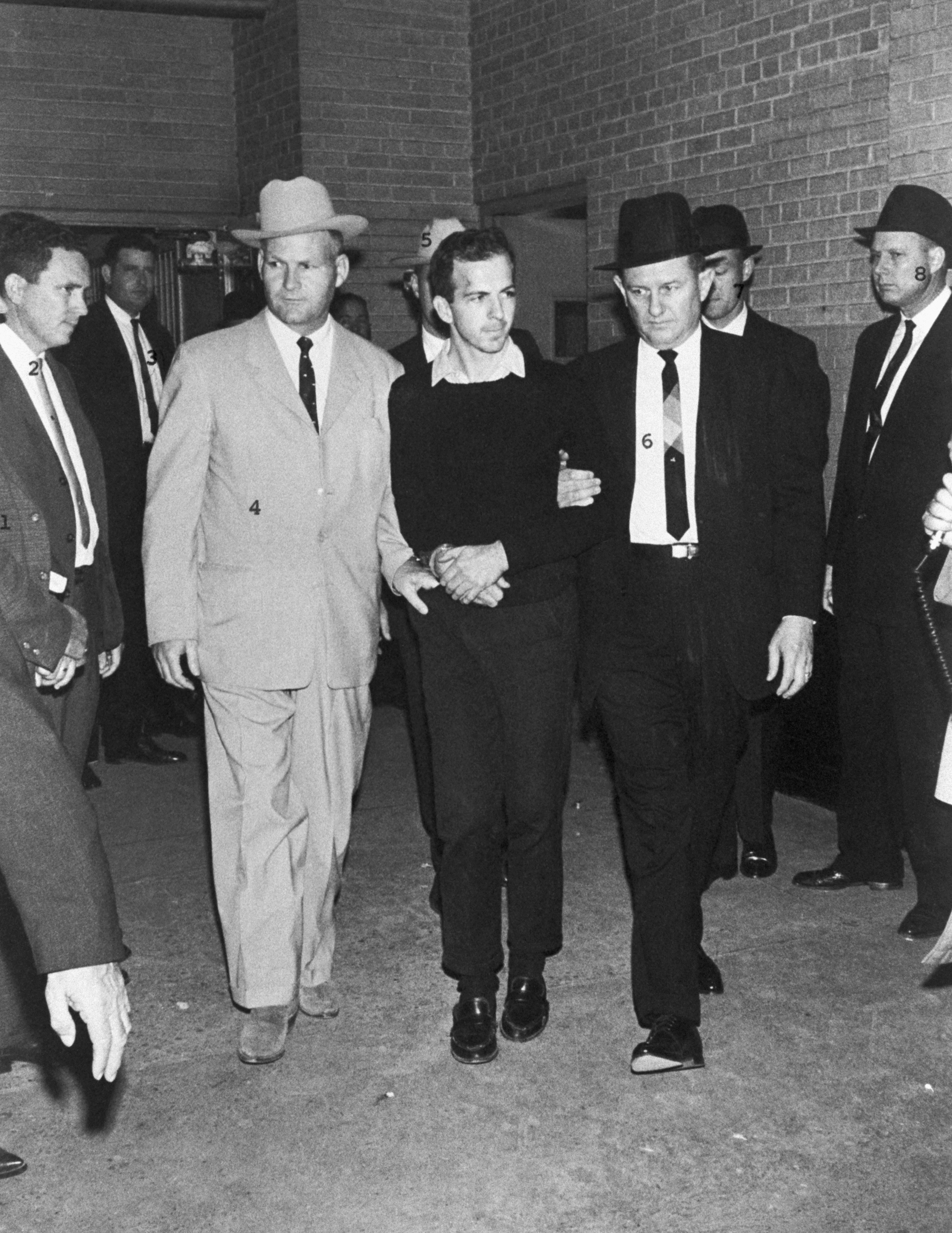Unos guardias escoltan a Lee Harvey Oswald dos días después de su detención en relación con el asesinato del presidente Kennedy. Oswald fue baleado por Jack Ruby durante una rueda de prensa (Foto de © CORBIS/Getty Images)