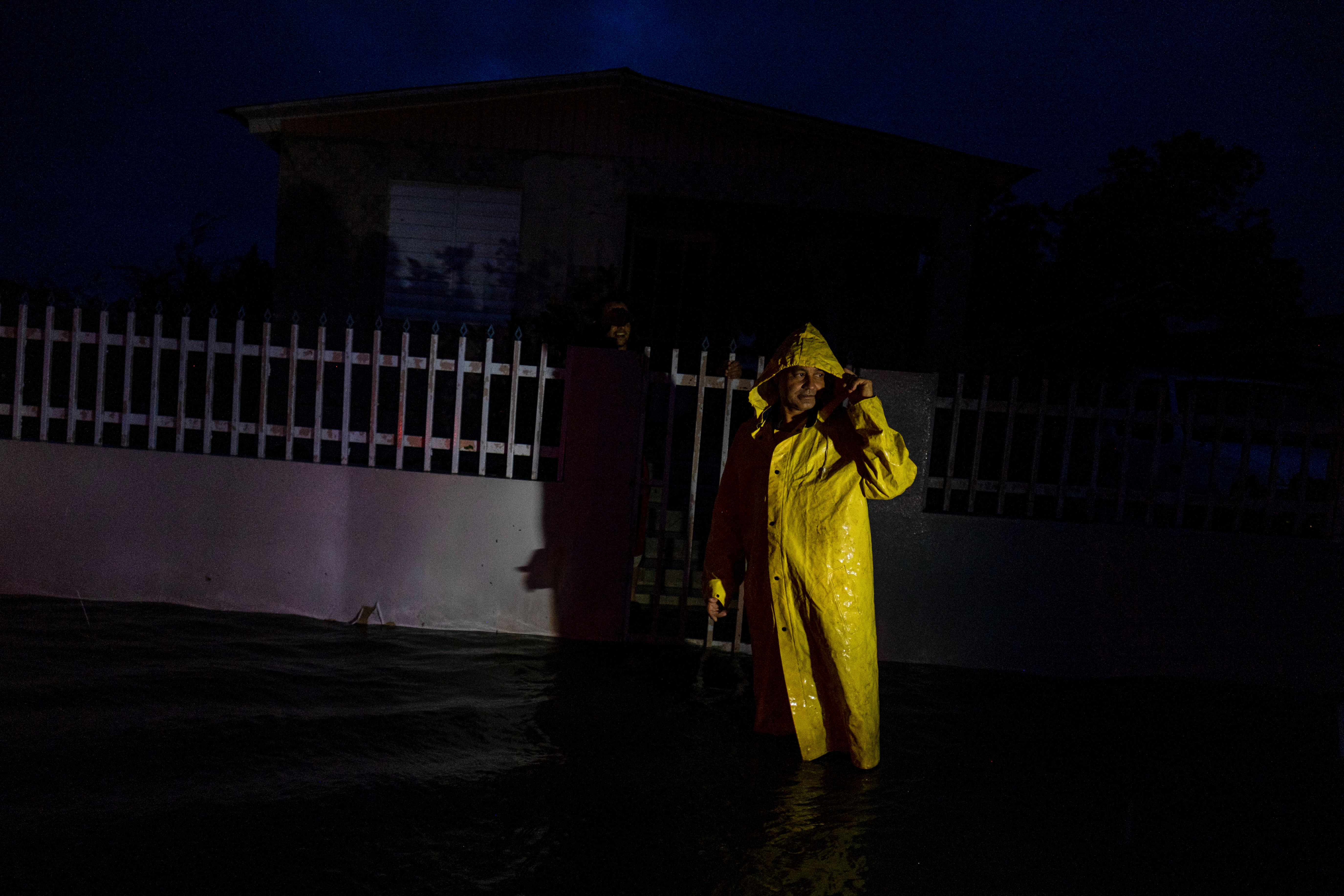 Un hombre con una cubierta para la lluvia se para en la oscuridad frente a una casa después de que el huracán Fiona tocara tierra en Guayanilla, Puerto Rico el 18 de septiembre de 2022. REUTERS/Ricardo Arduengo
