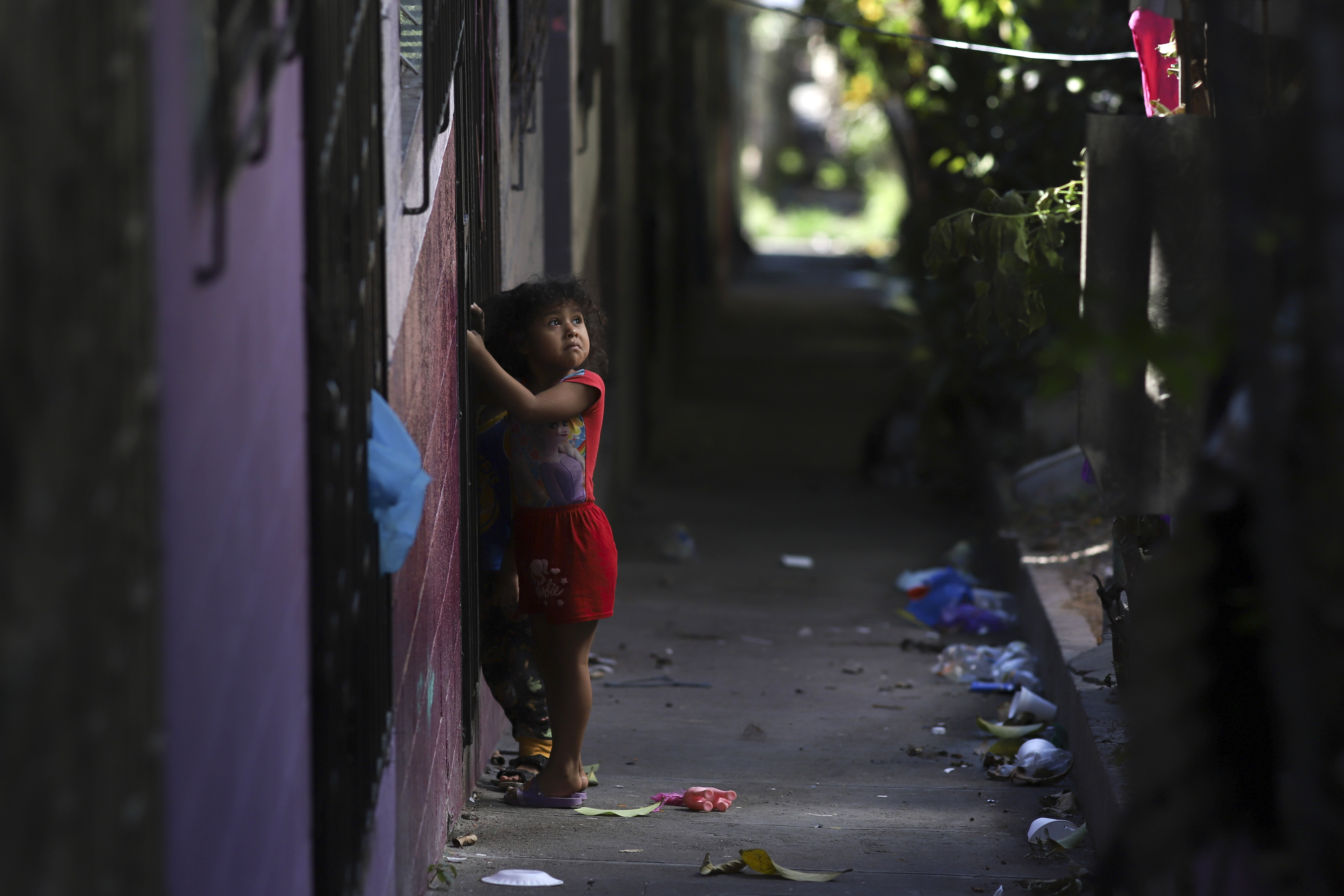 A girl stands by her house, dismantled by members of the Barrio 18 gang in the La Campanera neighborhood, in Soyapango, El Salvador, on January 27, 2023. At least 500 houses were dismantled by gang members and employees. for the consumption and sale of drugs after expelling their owners.  (AP Photo/Salvador Melendez)