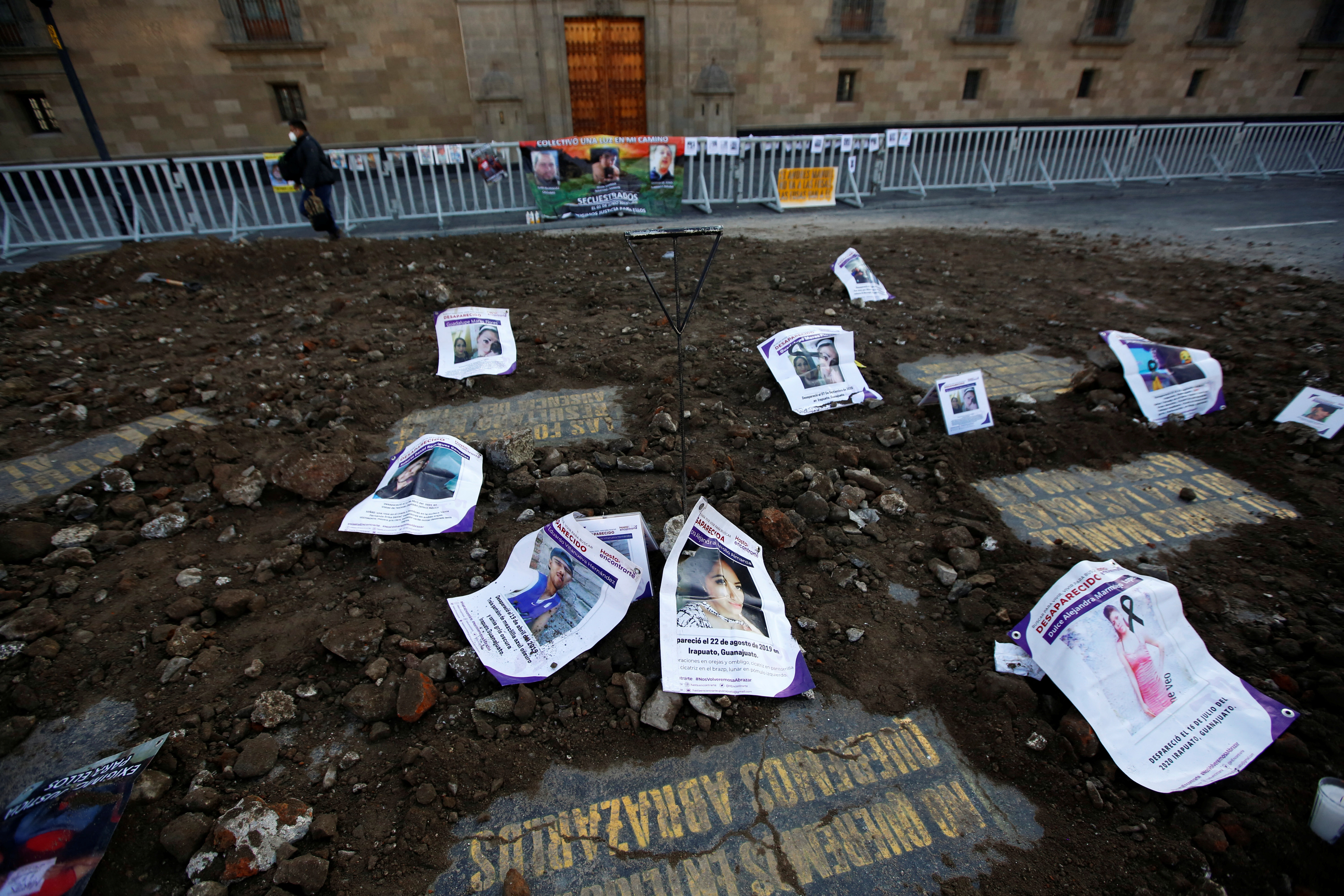 Flyers and posters with information on missing persons in the state of Guanajuato are placed on simulated clandestine graves arranged by their relatives during a protest outside the National Palace in Mexico City, Mexico December 13, 2021. REUTERS/Gustavo Graf