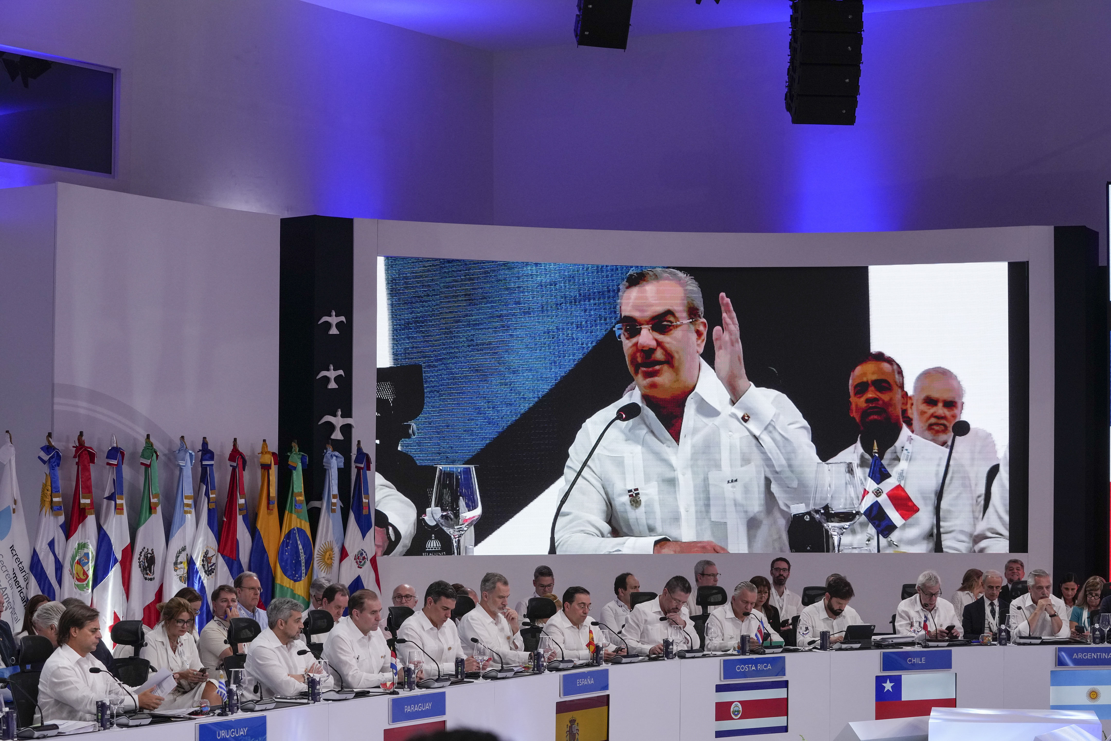 Líderes iberoamericanos escuchan el discurso del presidente de República Dominicana, Luis Abinader, en la pantalla, durante la sesión de la 28va Cumbre Iberoamericana, en Santo Domingo, República Dominicana, el sábado 25 de marzo de 2022. (Foto AP/Ariana Cubillos)