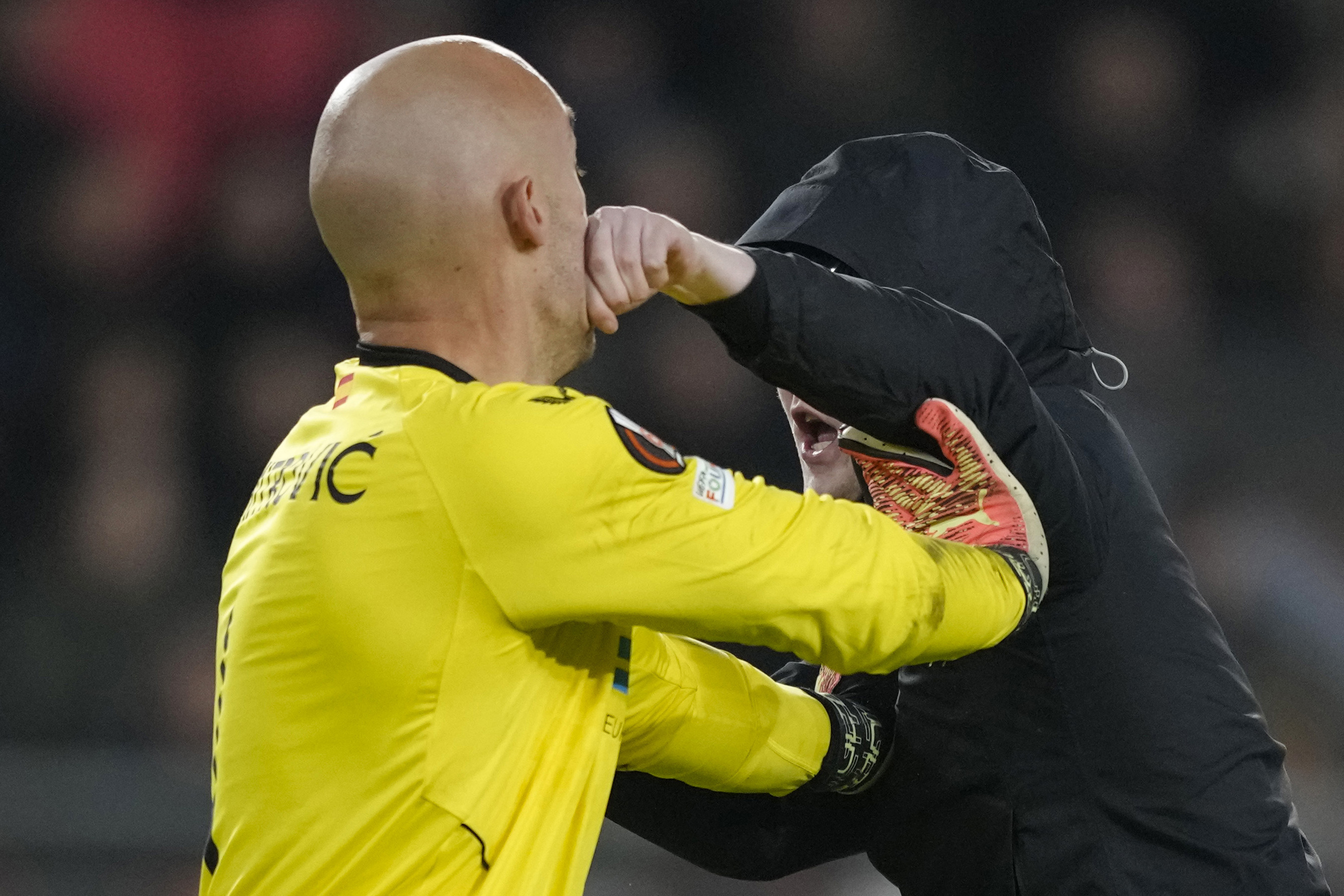 Un aficionado del PSV Eindhoven propina un puñetazo al arquero del Sevilla Marko Dmitrovic durante el partido de la Liga Europa, el jueves 23 de febrero de 2023, en Eindhoven, Países Bajos. (AP Foto/Peter Dejong)