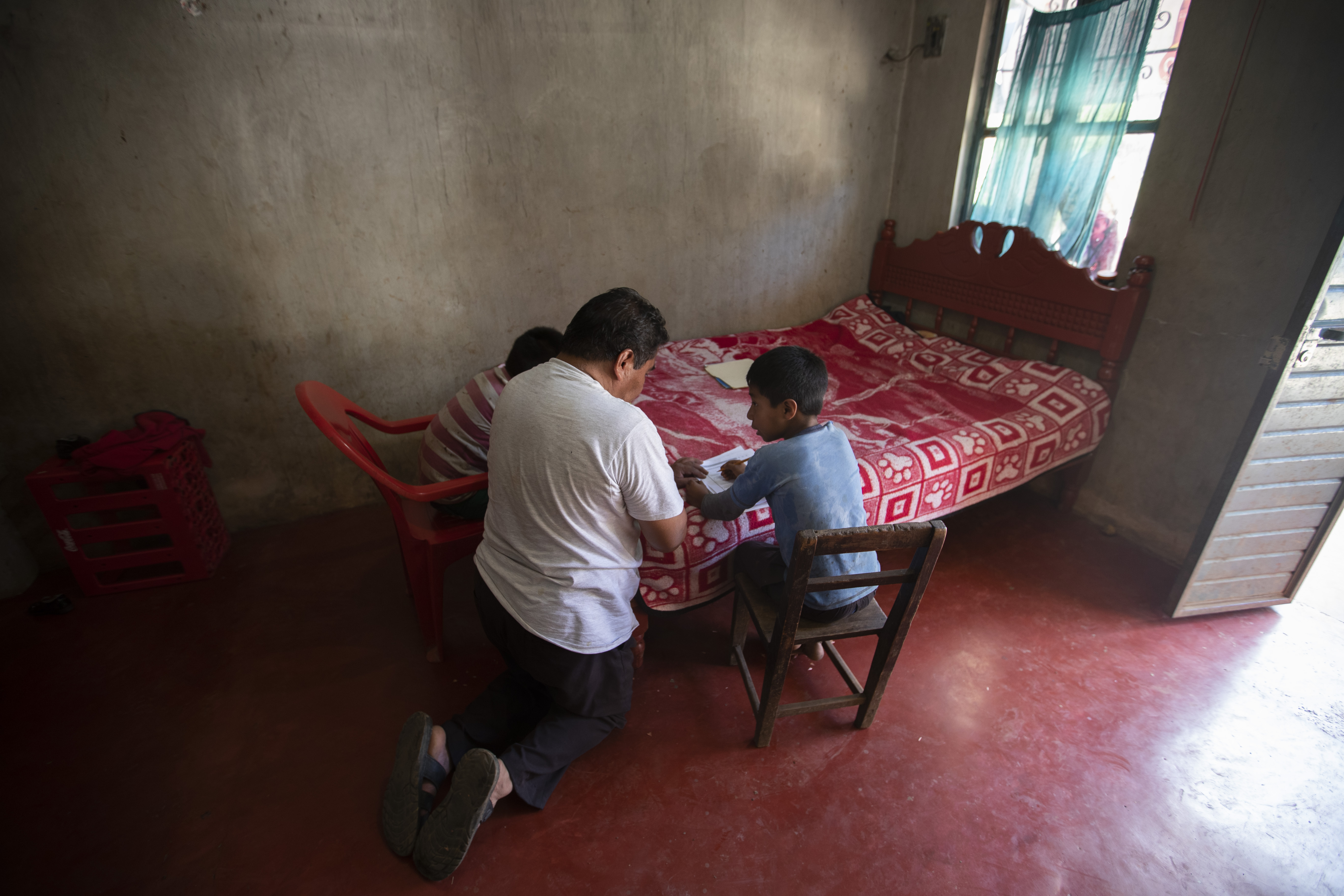 Usando una cama como escritorio, Agustín Vázquez ayuda a sus hijos Samuel y Héctor con sus tareas escolares entregadas por maestros en medio de la nueva pandemia de coronavirus en su casa en Nuevo Yibeljoj, estado de Chiapas, México, el viernes 11 de septiembre de 2020. “Lo intento , pero no es lo mismo que un maestro, porque yo soy agricultor ”, dijo Agustín.