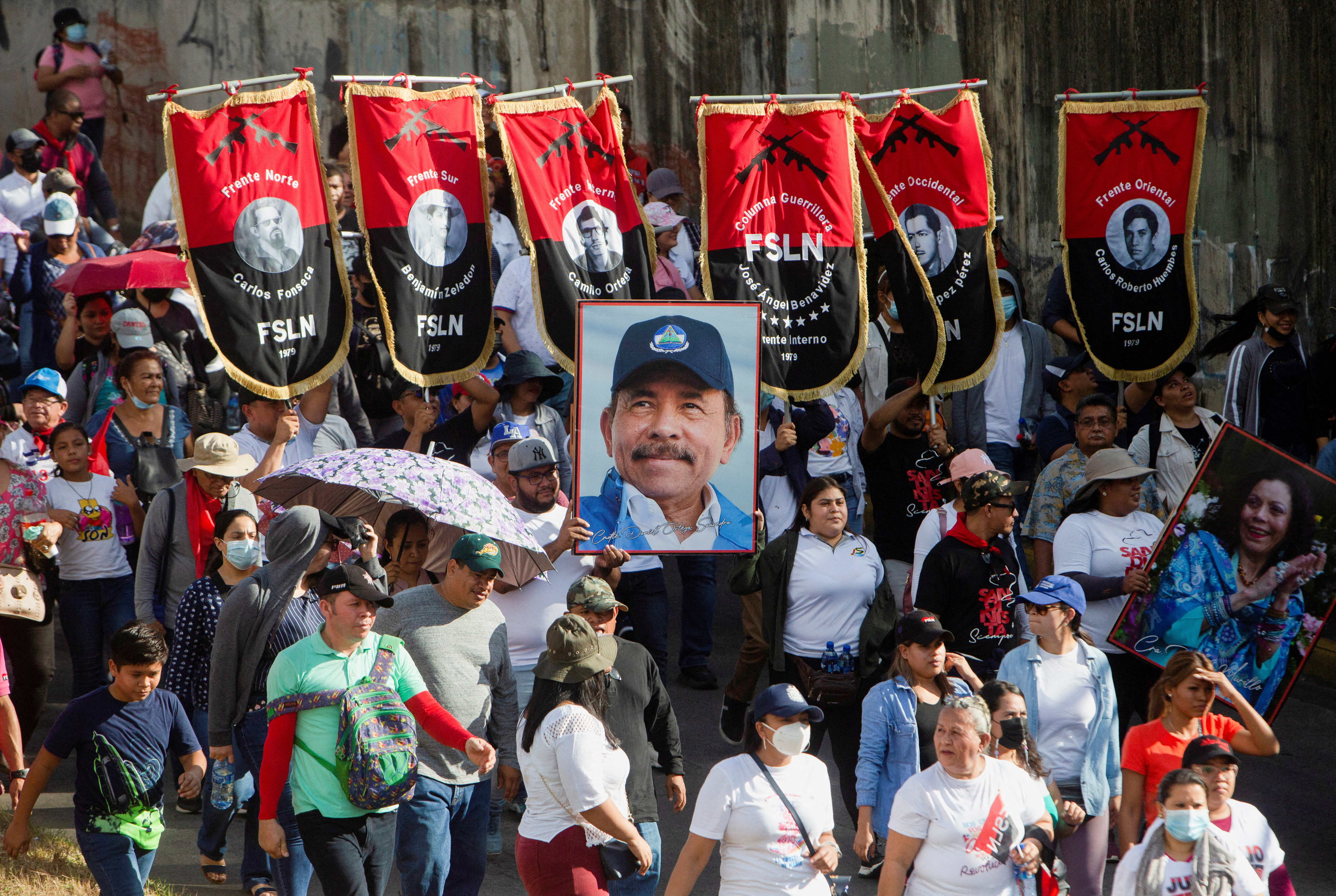 Simpatizantes llevan pancartas del Frente Sandinista de Liberación Nacional (FSLN) y un retrato del presidente Daniel Ortega, mientras participan en una marcha progubernamental en Managua, Nicaragua, el 11 de febrero de 2023 (REUTERS/Stringer)