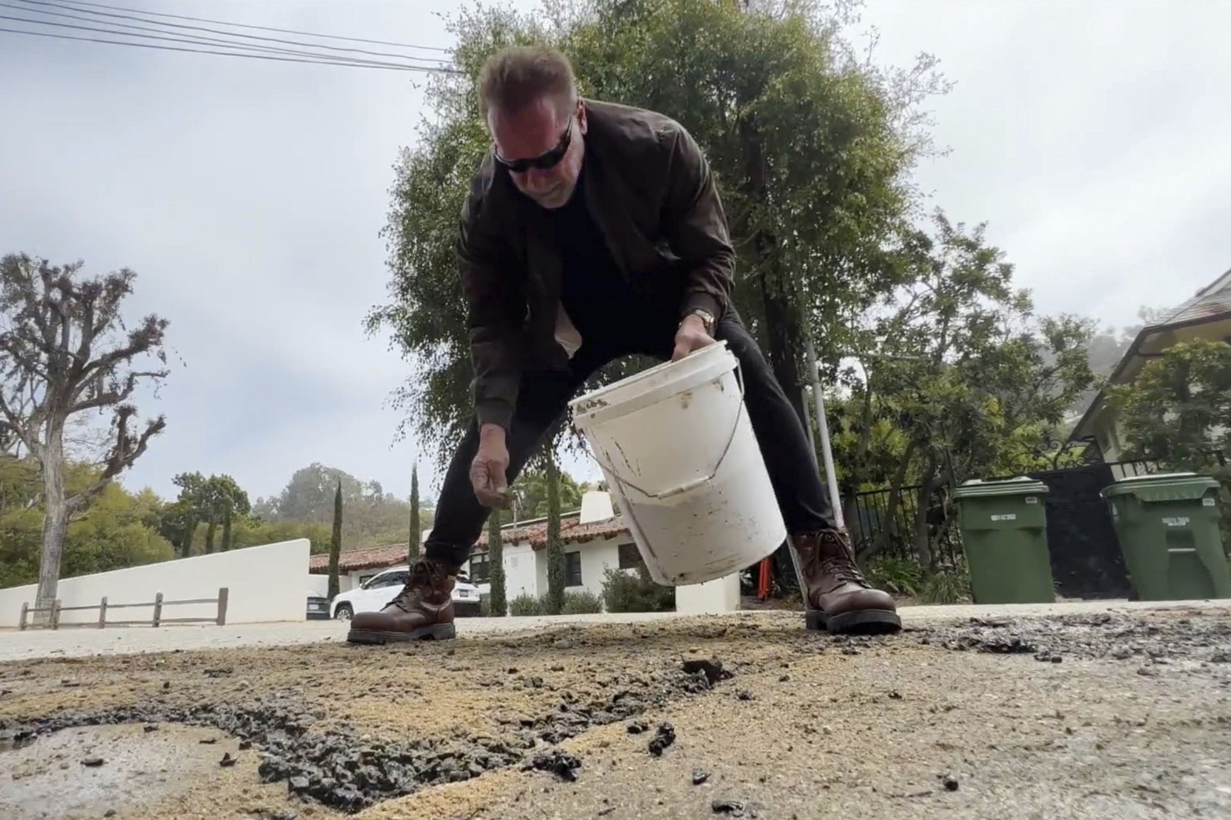 El actor y ex gobernador de California tuiteó un video el martes de él y un ayudante usando concreto empaquetado para reparar la carretera en el área de Brentwood. (Arnold Schwarzenegger via AP)