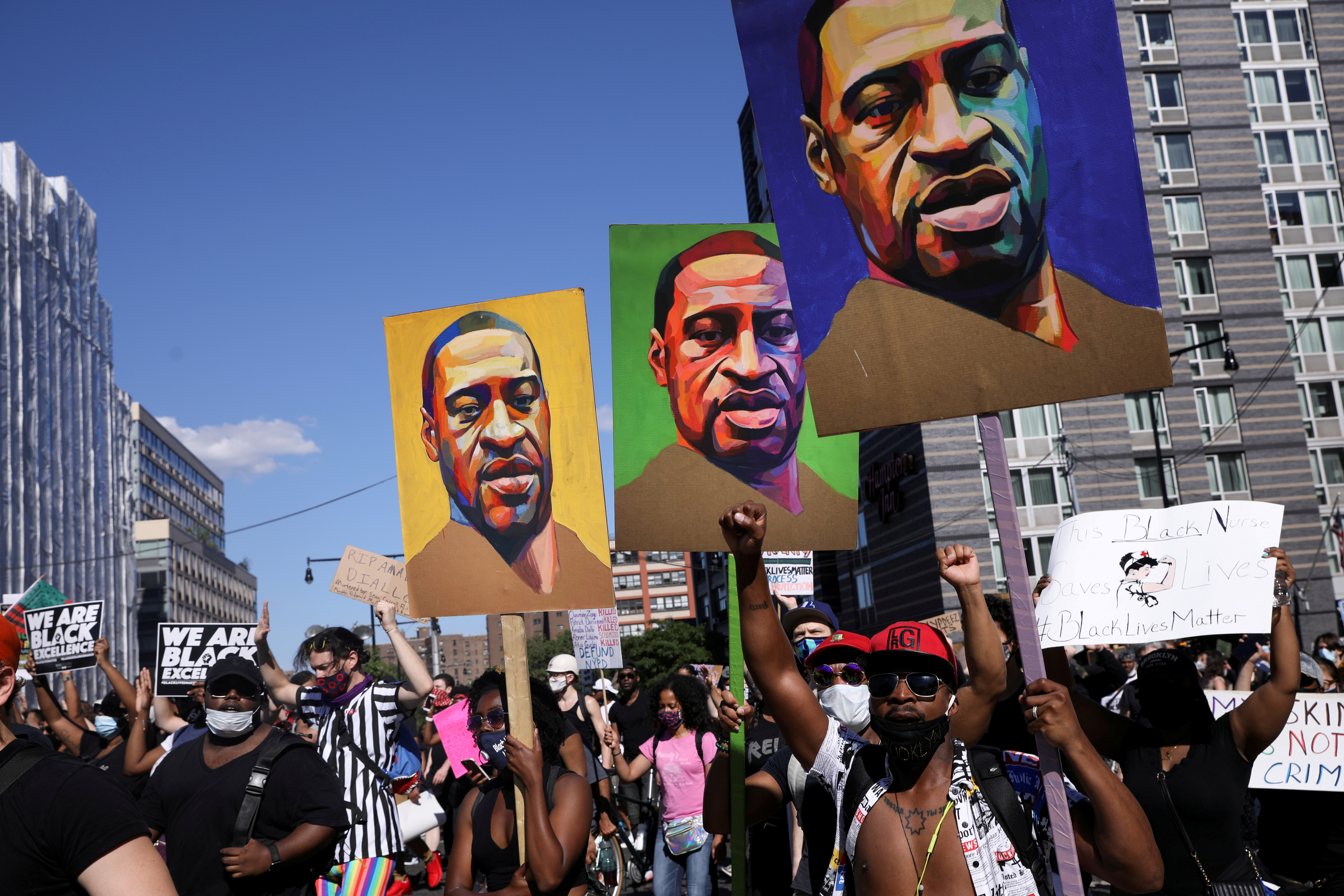 FOTO DE ARCHIVO: Manifestantes sostienen pancartas con una imagen del rostro de George Floyd durante una protesta contra la brutalidad policial y la desigualdad racial en Brooklyn, Nueva York (REUTERS/Caitlin Ochs)