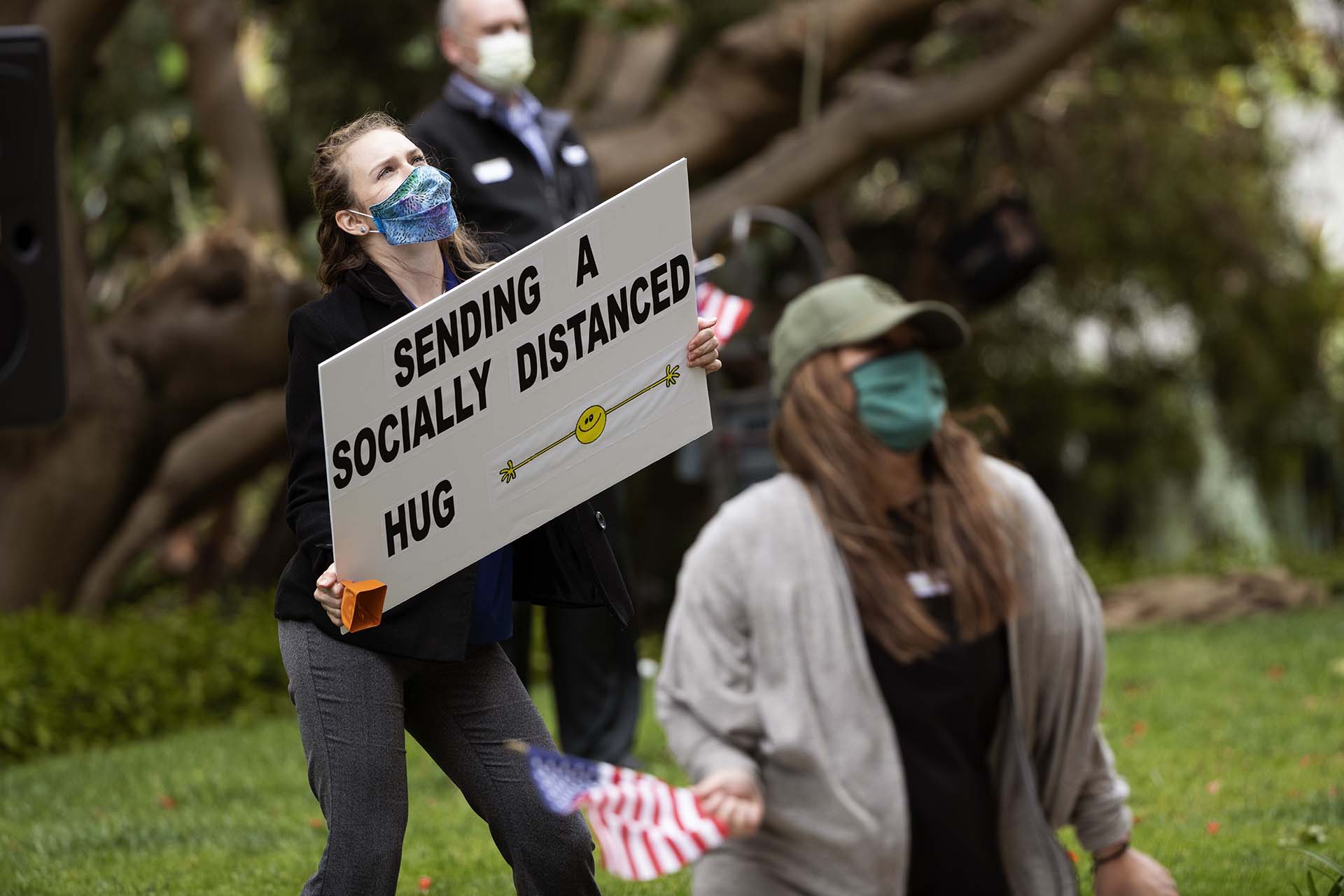 Empleados de Vi en el complejo del retiro La Jolla sostienen carteles y banderas para los residentes en San Diego (AP Photo/Gregory Bull)