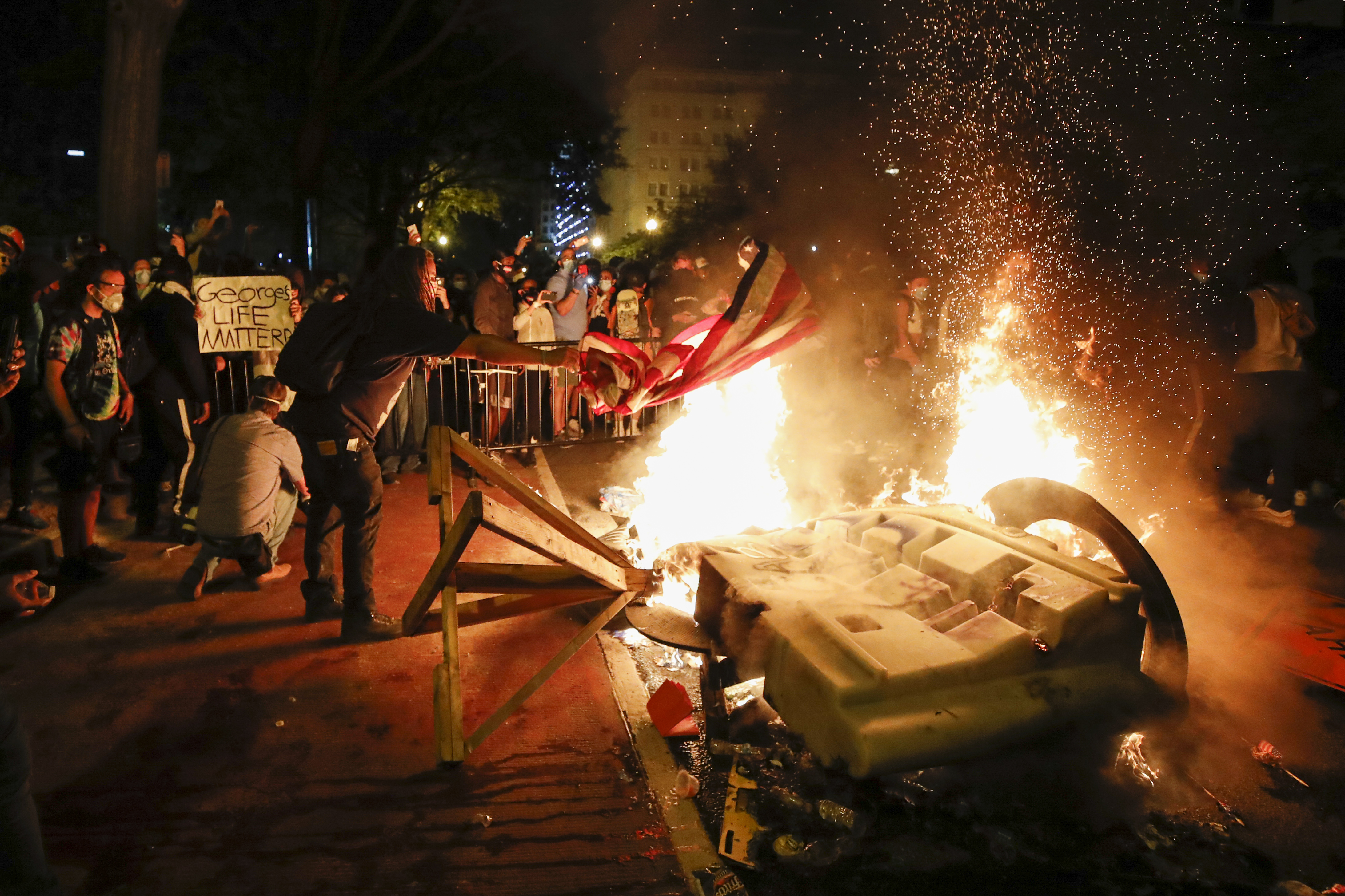 Y como ha ocurrido en otras ciudades en los últimos días, después de un ataque contra un coche patrulla en la calle 14, la policía lanzó pelotas de goma y cargó contra los presentes, incluidos varios periodistas. En la foto, manifestantes comienzan un incendio cerca de la Casa Blanca en Washington (AP Photo/Alex Brandon)