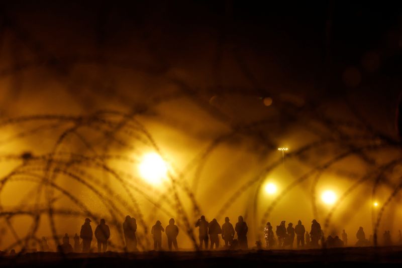 Migrantes de pie cerca del muro que separa la frontera entre EEUU y México durante una tormenta de arena, en El Paso, Texas, EEUU. 10 de mayo de 2023. REUTERS/Jose Luis Gonzalez