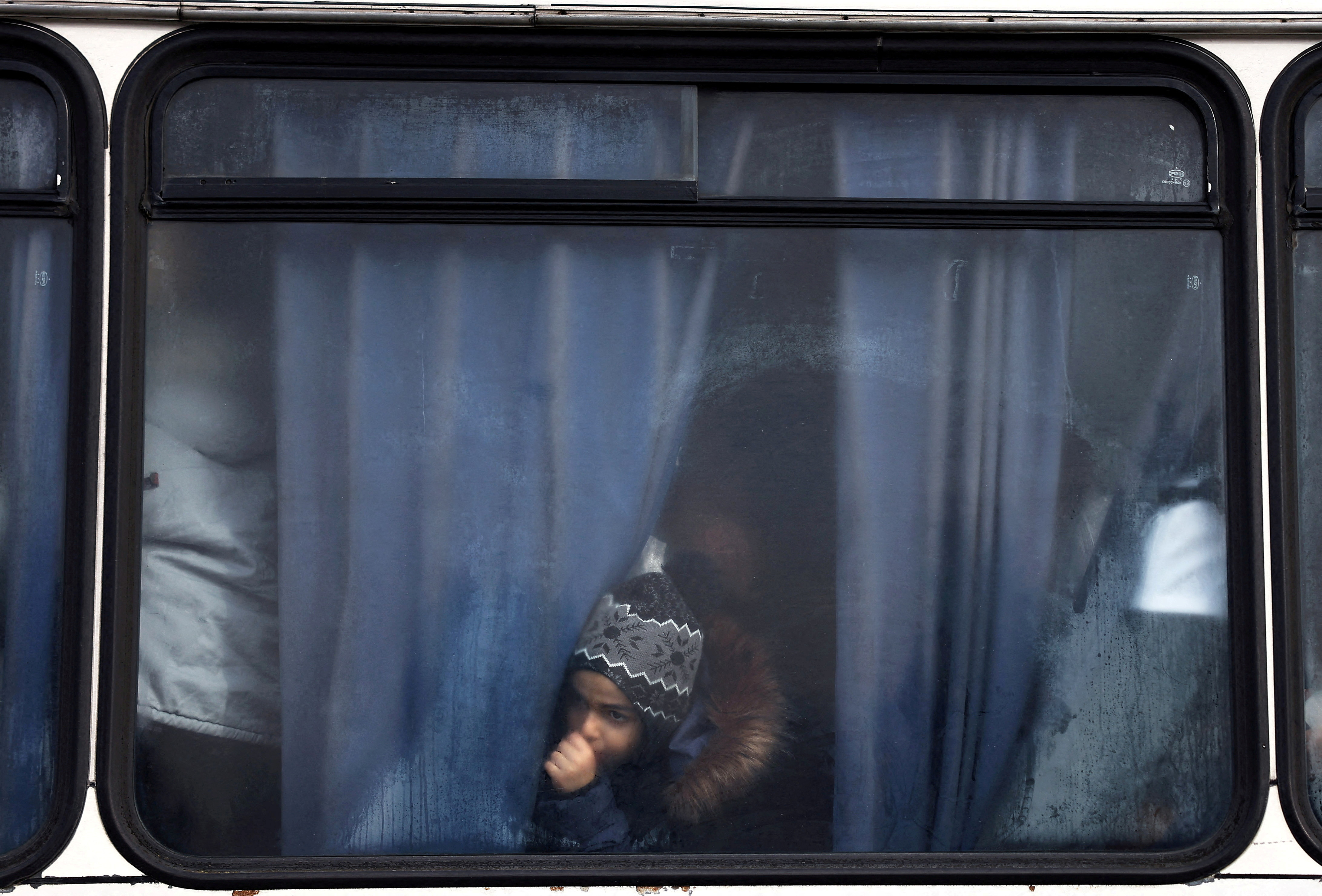 Un niño mira por la ventana de un autobús después de huir de Ucrania cuando llega al pueblo de Moszczany, cerca del puesto de control fronterizo en Korczowa, Polonia, el 1 de marzo de 2022. (REUTERS/Kai Pfaffenbach)