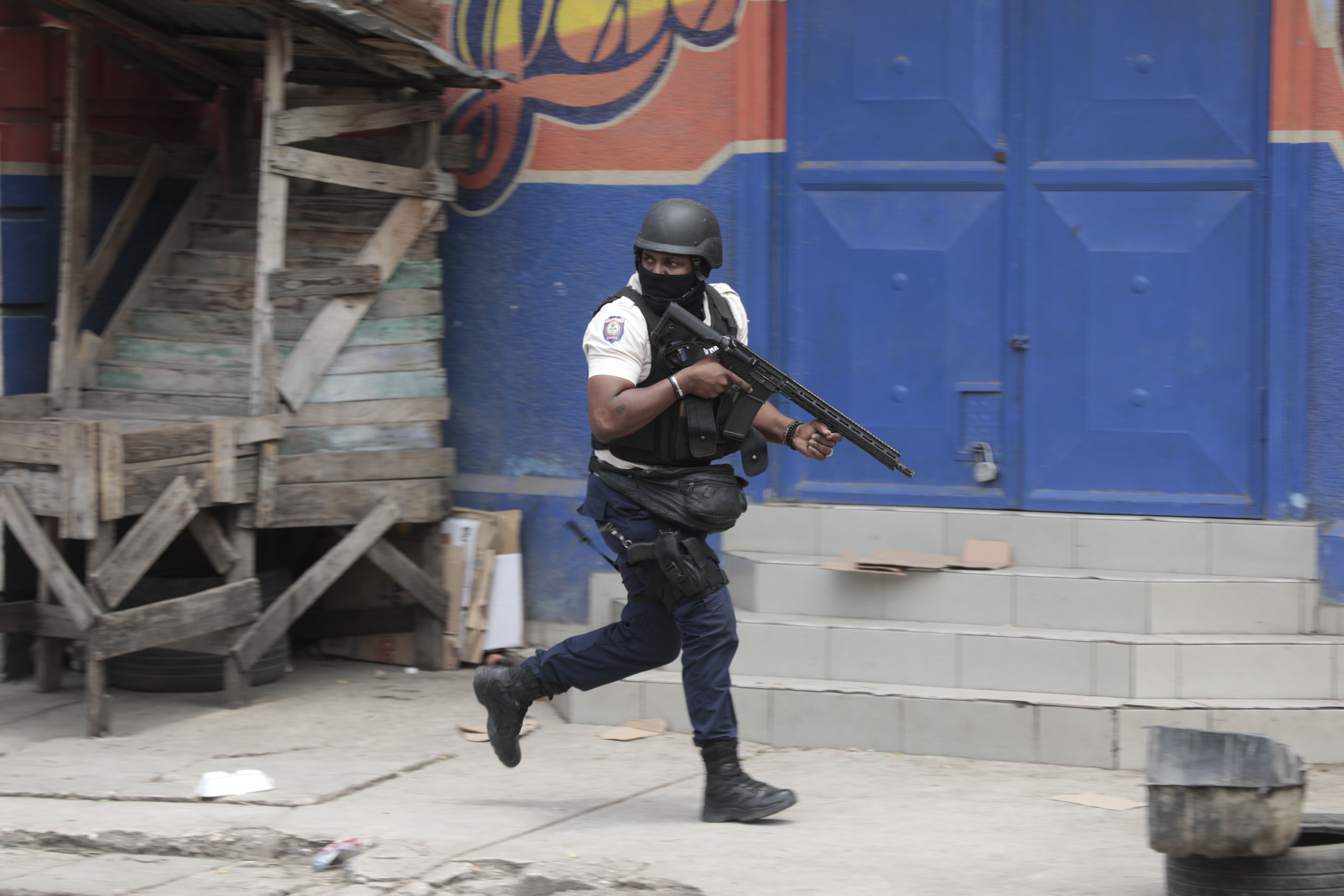 Un policía se resguarda durante un operativo antipandillas en el vecindario Portail, el martes 25 de abril de 2023, en Puerto Príncipe. (AP Foto/Odelyn Joseph)