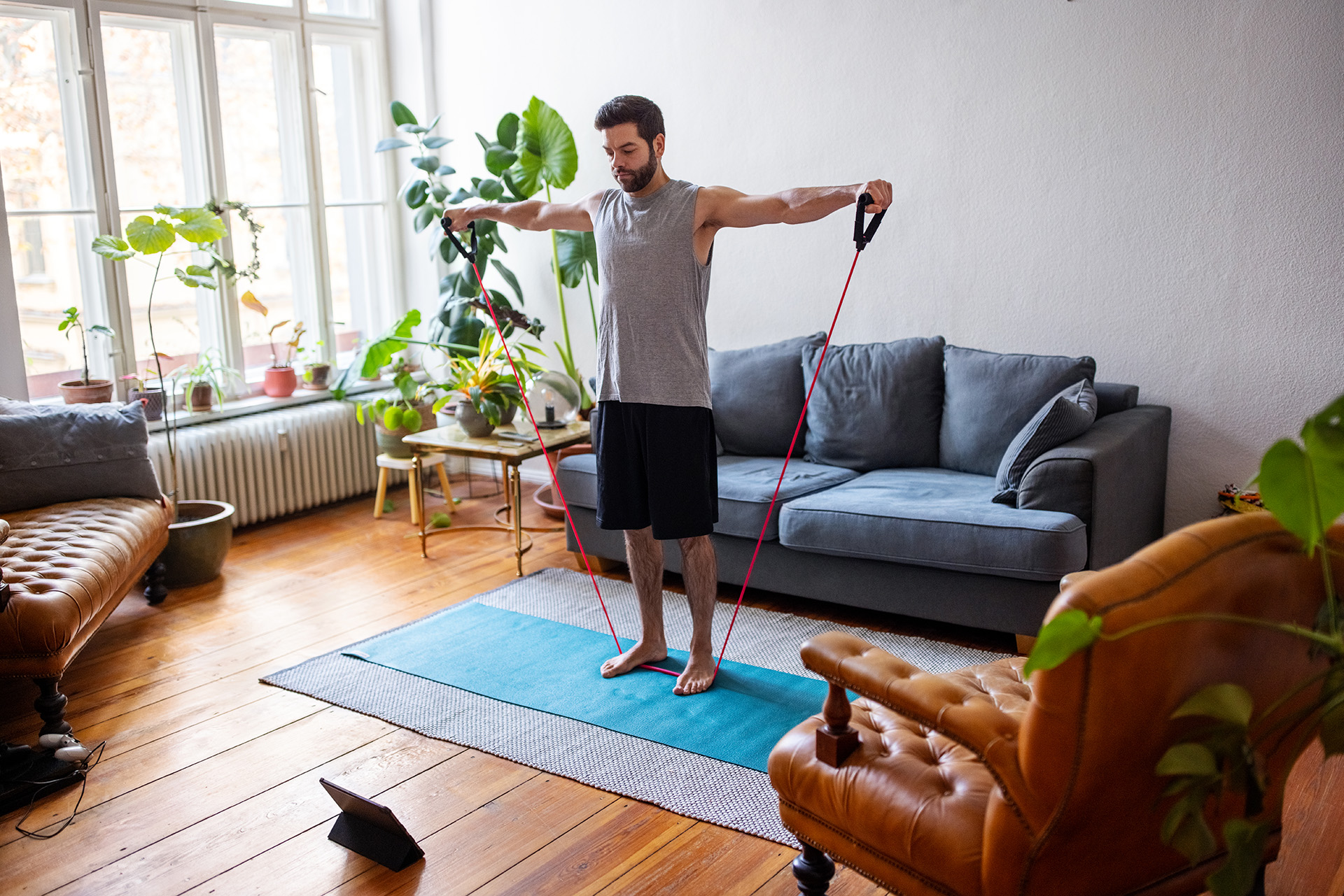 Man exercising with stretching band at home with a digital tablet. Mid adult man using an elastic rubber band following a tutorial online and exercise at home during isolation for Covid - 19 at home. (Getty Images)