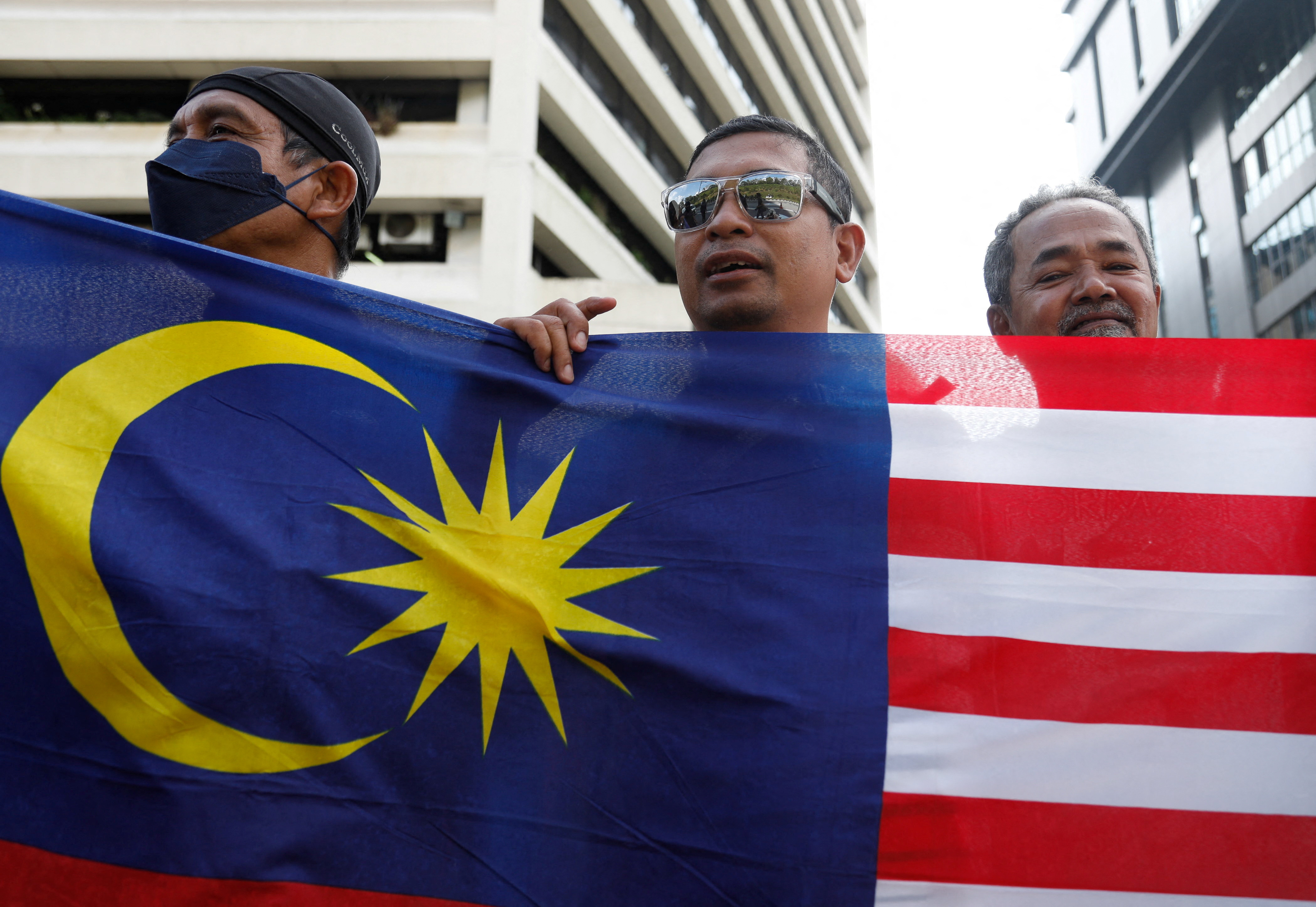 Supporters of Anwar Ibrahim hold the Malaysian flag as they celebrate Anwar's swearing in as prime minister in front of the National Palace in Kuala Lumpur, Malaysia November 24, 2022. REUTERS/Hasnoor Hussain/Pool