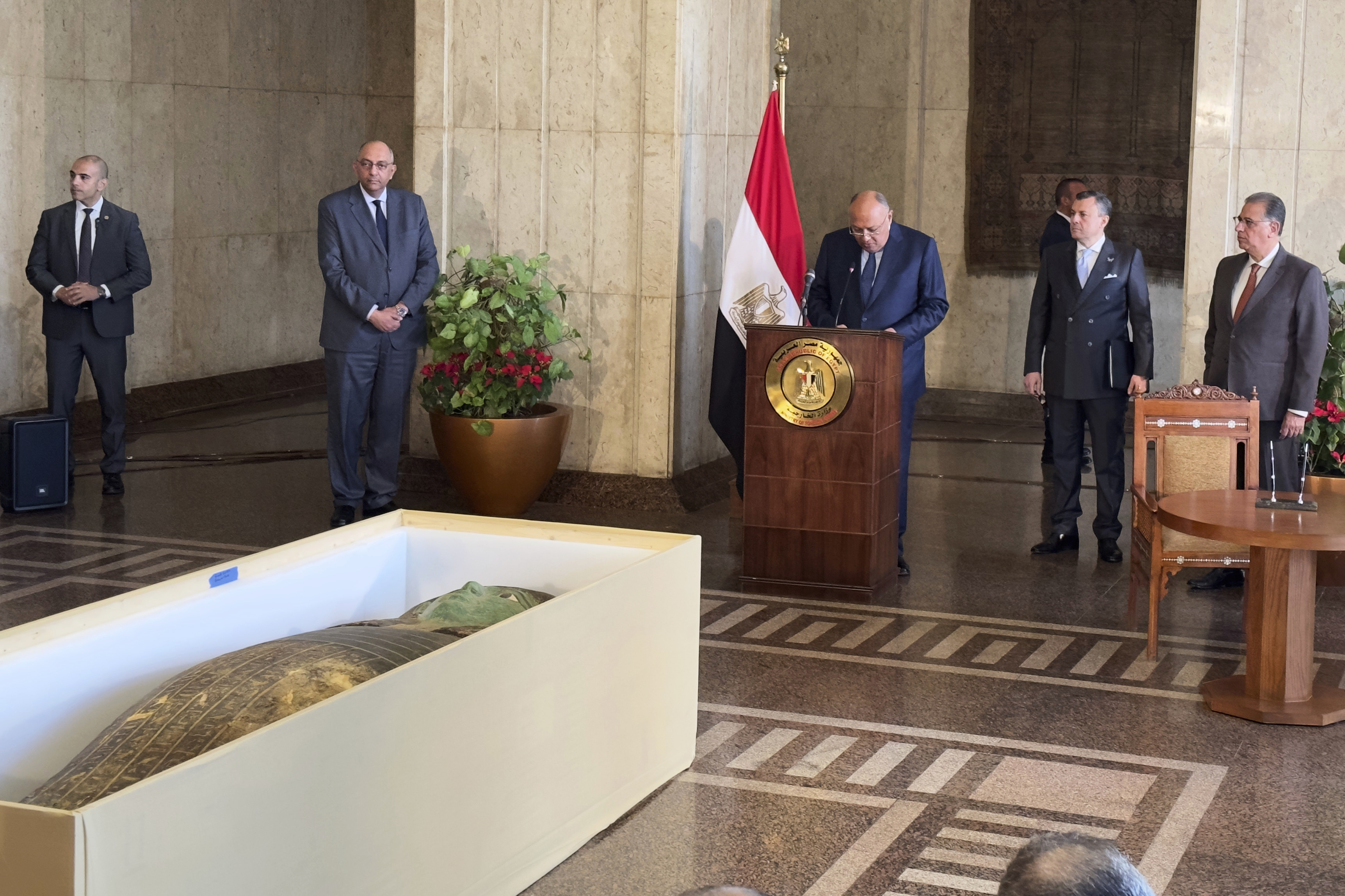 El ministro de Relaciones Exteriores, Sameh Shoukry, en el centro, de pie frente a un antiguo sarcófago de madera, habla durante una ceremonia de entrega en el Ministerio de Relaciones Exteriores en El Cairo, Egipto, el lunes 2 de enero de 2023. (Foto AP/Mohamed Salah)

