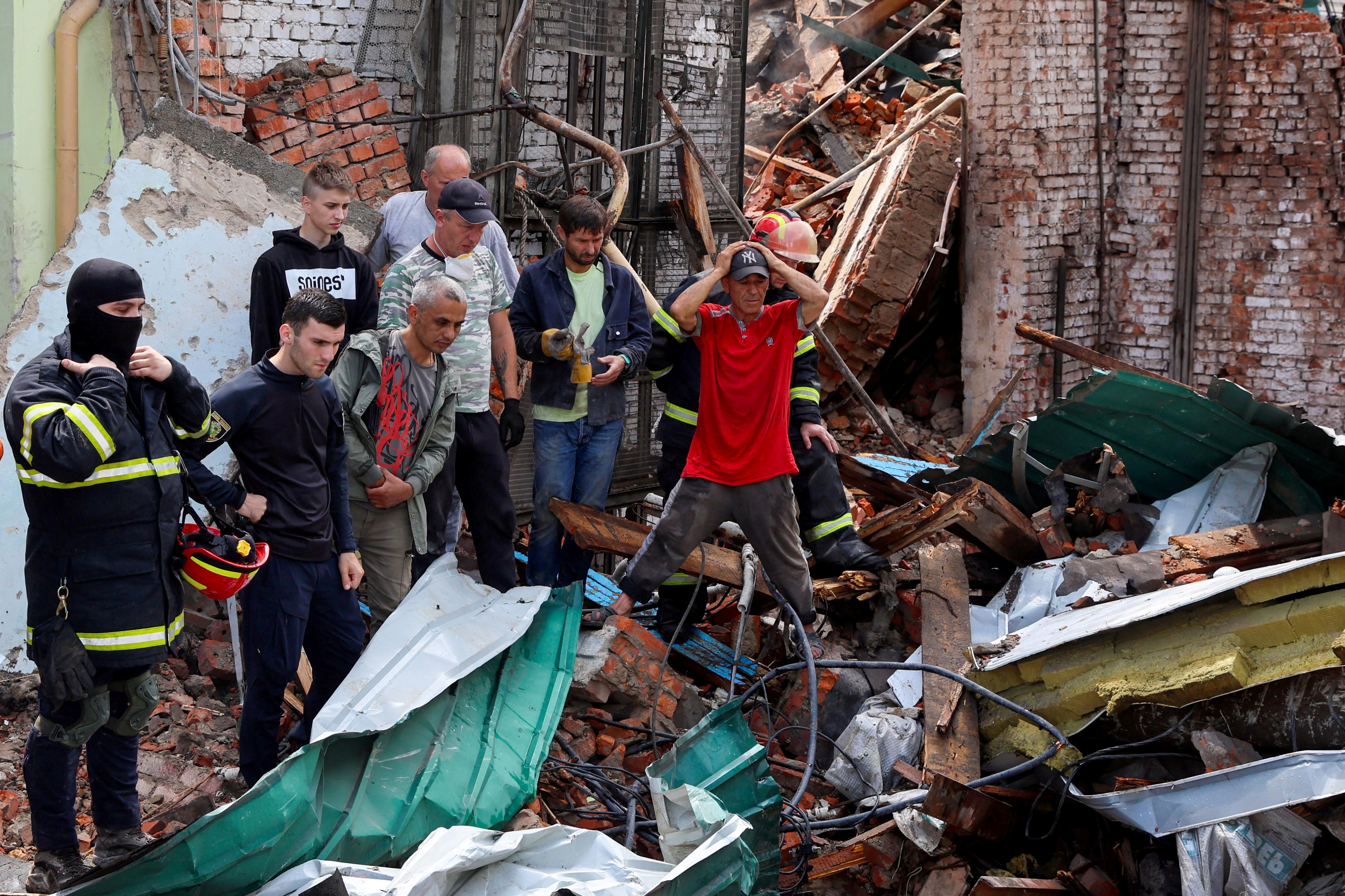 Un hombre reacciona mientras los rescatistas trabajan para sacar el cuerpo de una mujer de los escombros en la Casa Central de la Cultura, después de que un ataque militar golpeara un edificio, mientras continúa la invasión rusa de Ucrania, en Chuhuiv, en la región de Kharkiv, Ucrania 26 de julio de 2022. REUTERS/Nacho Doce