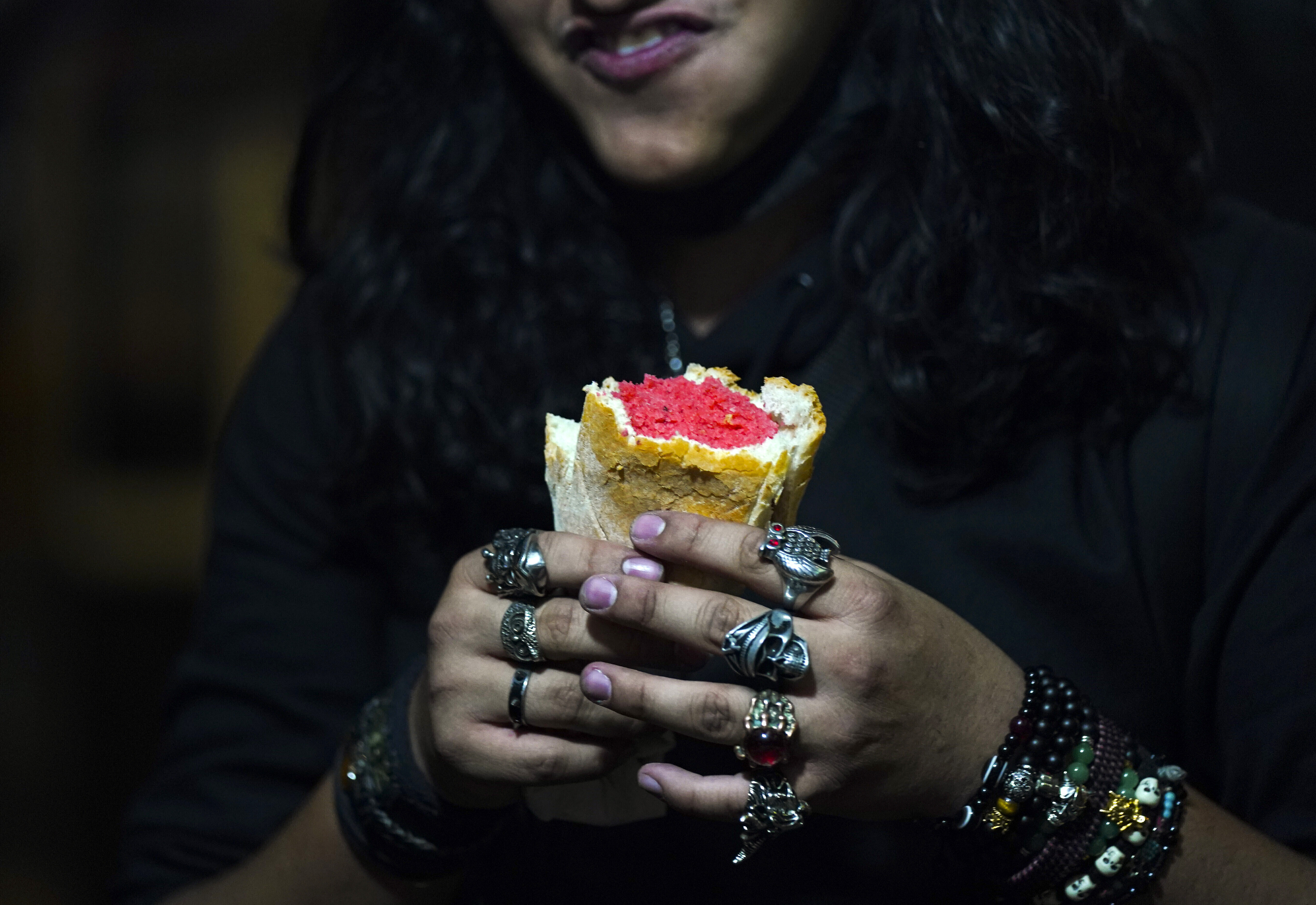 A young man who plays guitar in a rock band eats a pink tamale before a concert, at a street tamale stand in downtown Mexico City, on January 26, 2023. The dish dates back to pre-Hispanic times. when the Olmecs, Mexicas and Mayans used it in religious rituals, offerings and tombs.  (AP Photo/Fernando Llano)